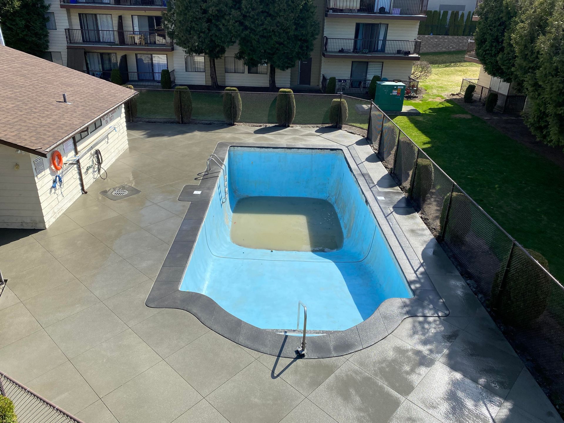 An aerial view of an empty swimming pool in front of a building