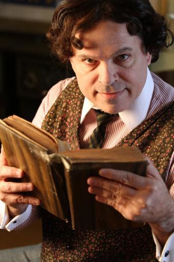 Close-up of man with curly dark hair holding an open book