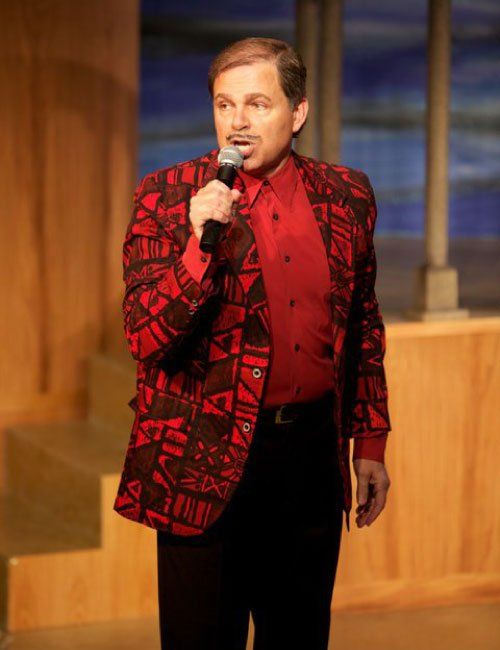 Phil in colorful jacket holding microphone and singing