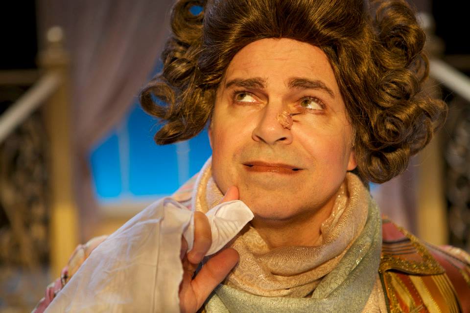 Close-up of actor onstage wearing brown wig and scarf