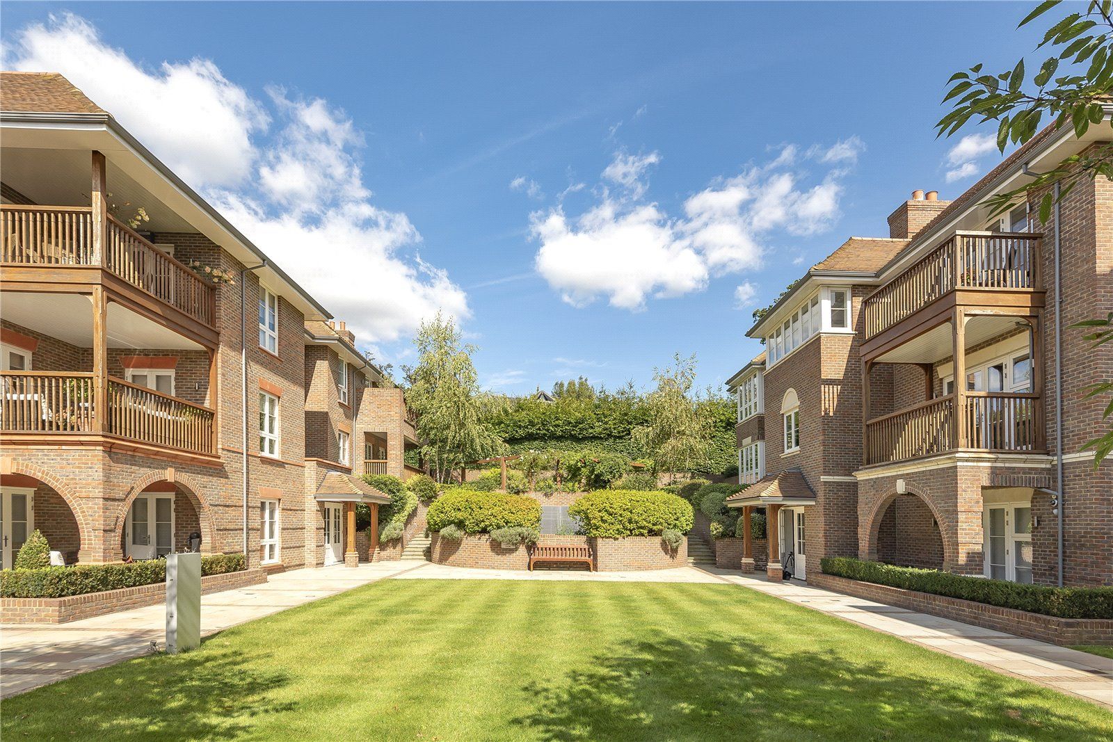 A row of brick buildings with a lush green lawn in the middle.