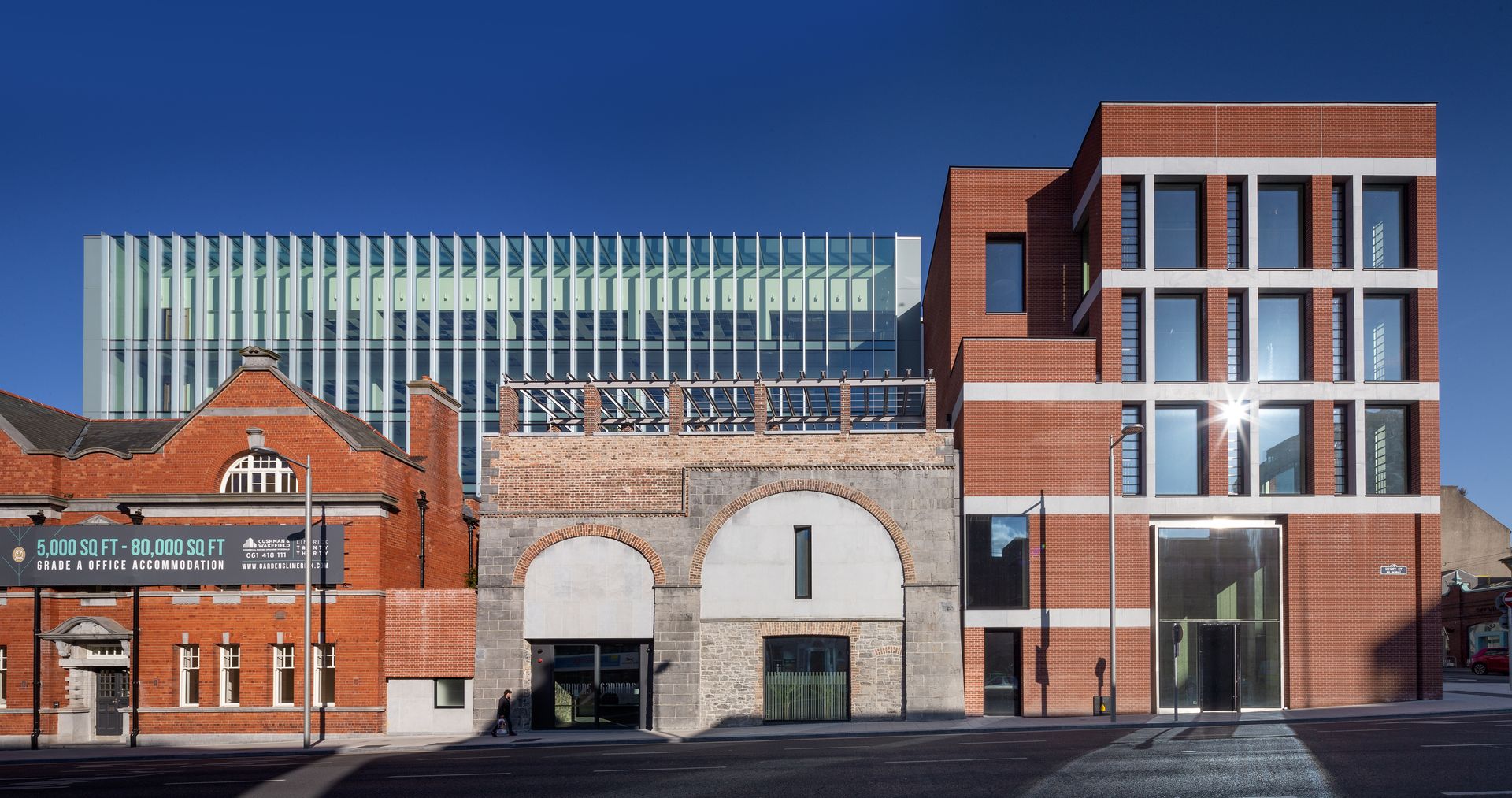 A large building with a lot of windows is next to a smaller building.