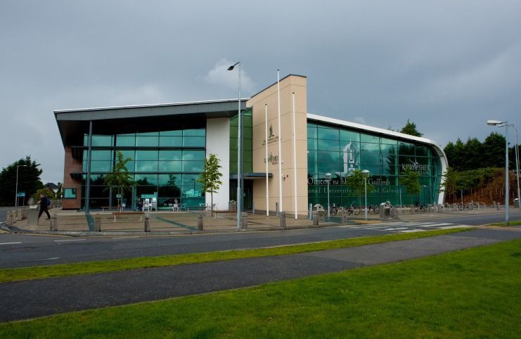 A large building with a lot of windows is sitting on the side of a road.