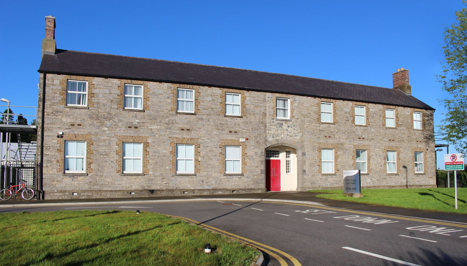 A large brick building with many windows and a red door