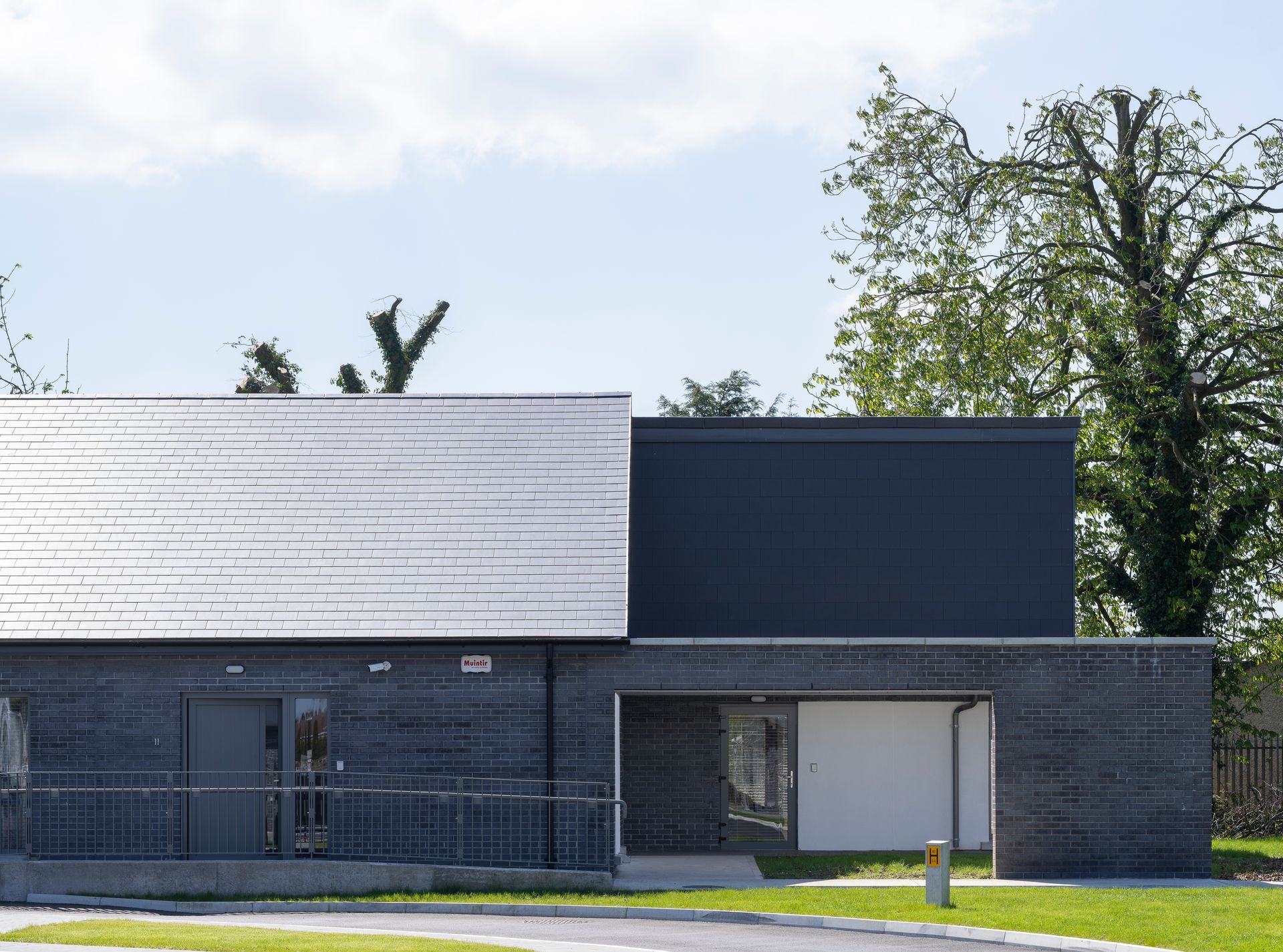 A black building with a white door is sitting on top of a lush green field.