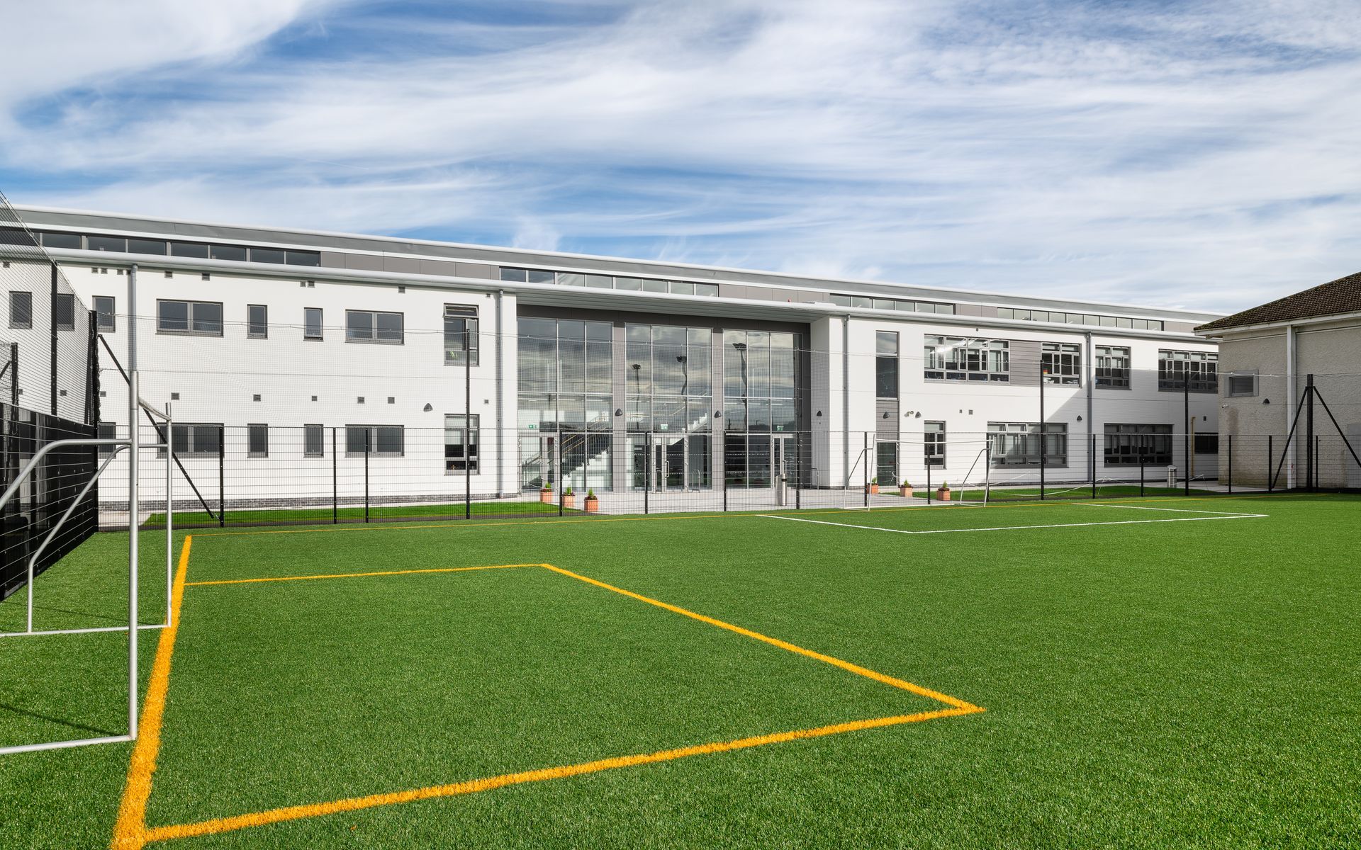 There is a soccer field in front of a large building.