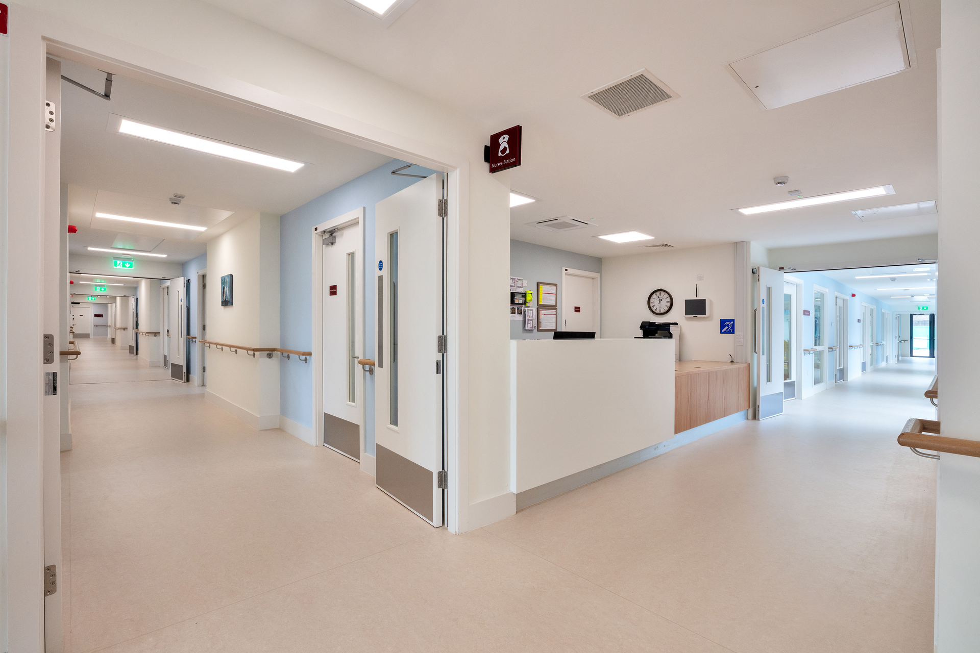A long hallway in a hospital with a reception desk.