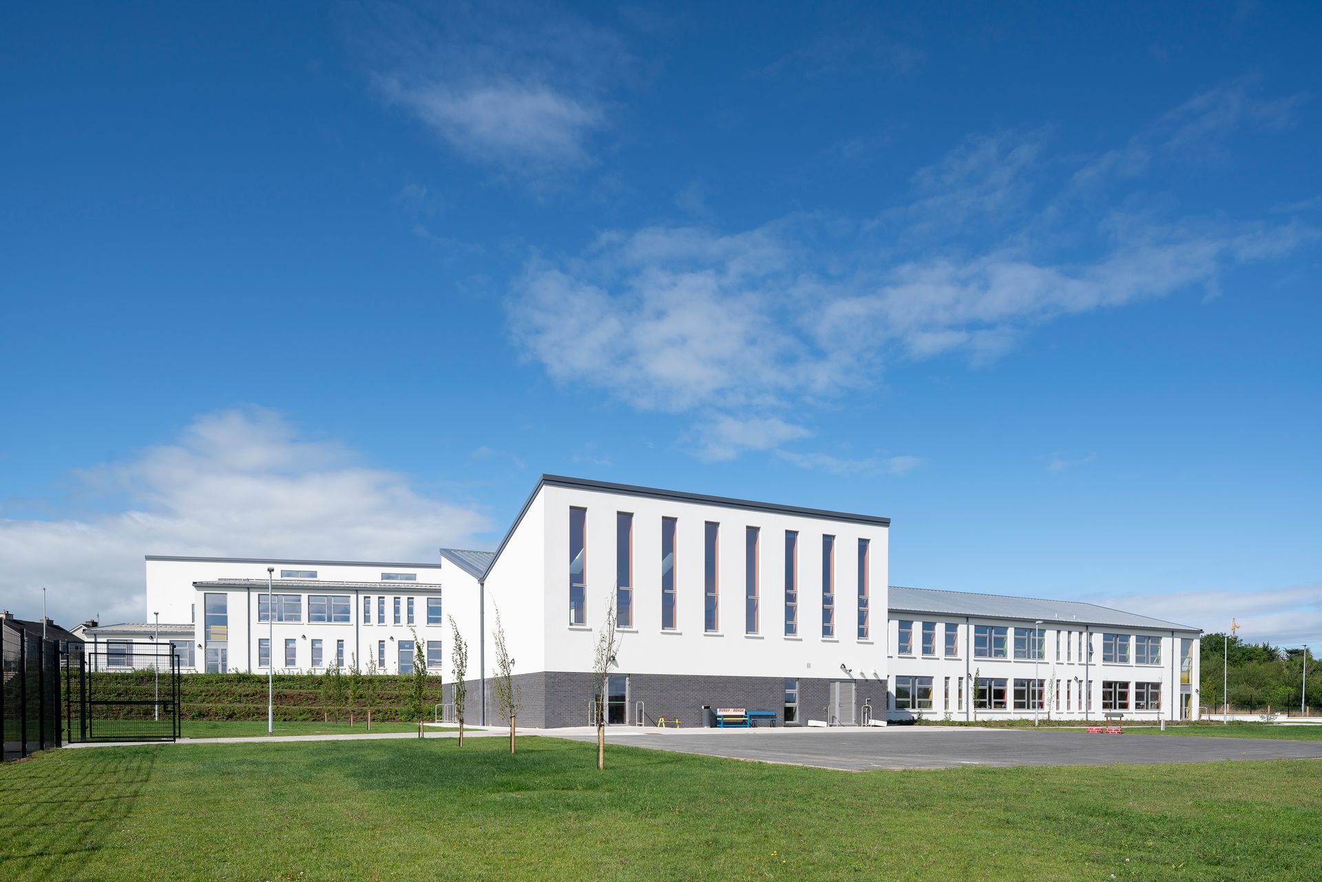 A large white building with a lot of windows is sitting on top of a lush green field.