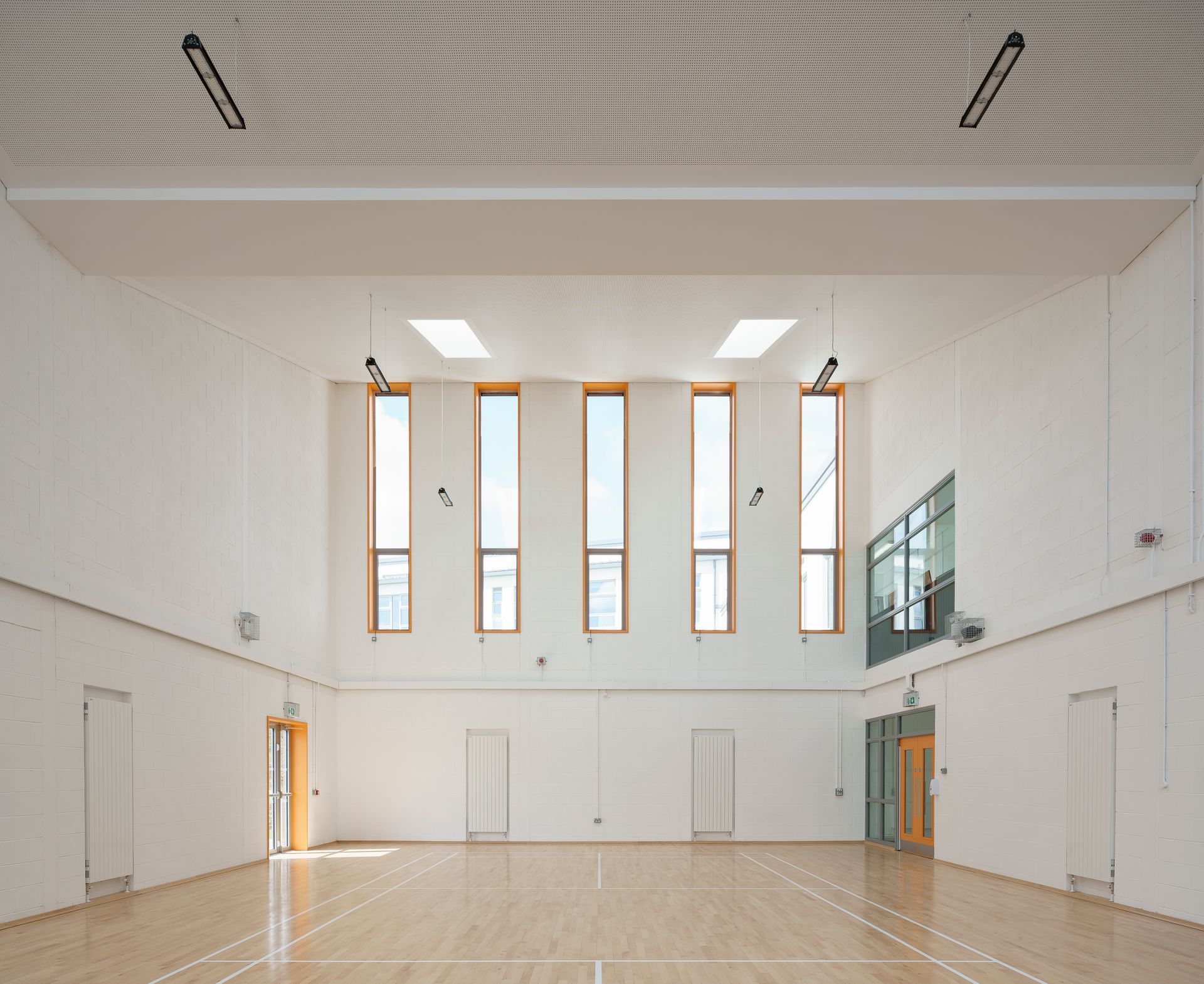 An empty gym with hardwood floors and white walls
