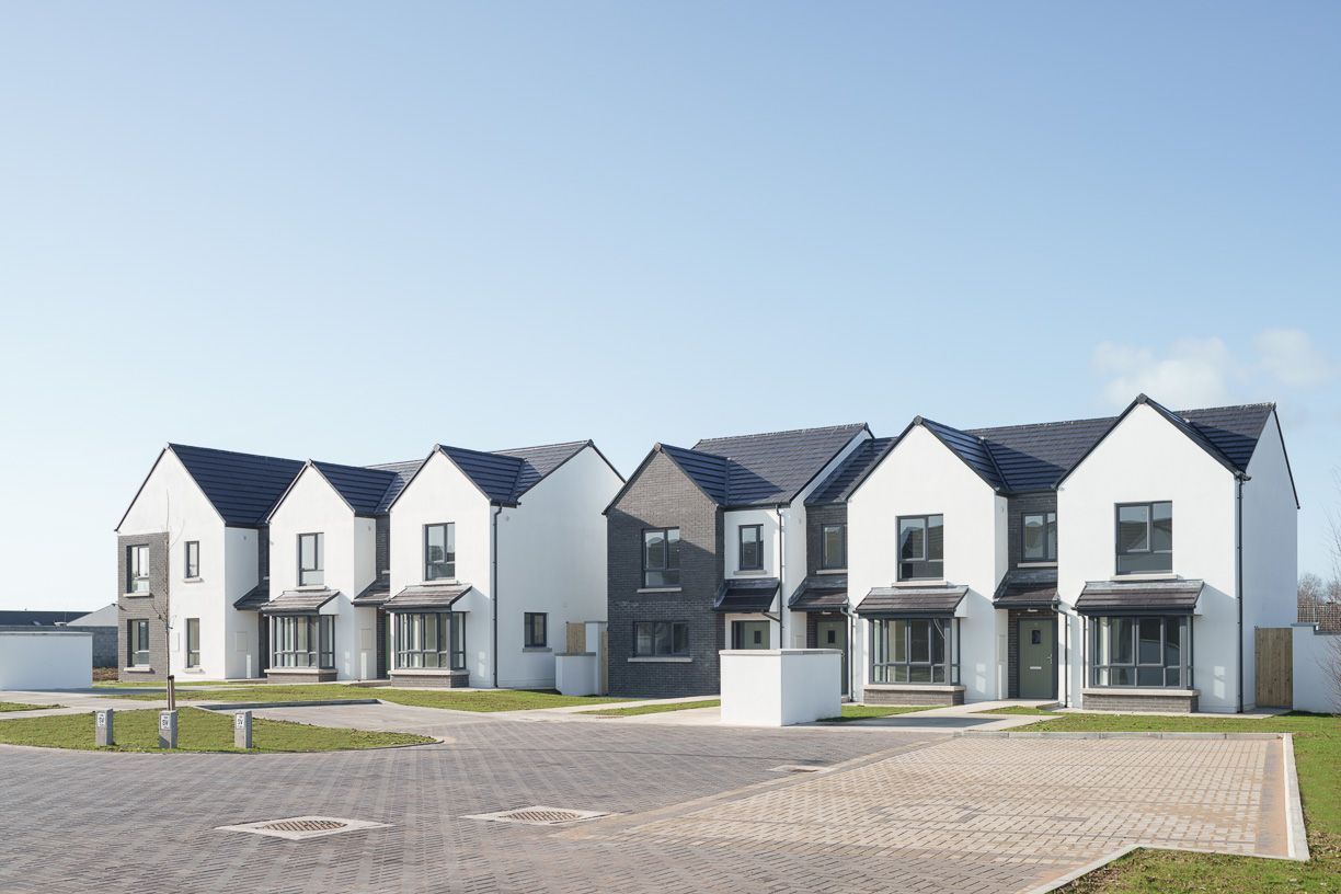A row of white houses with black roofs in a residential area.