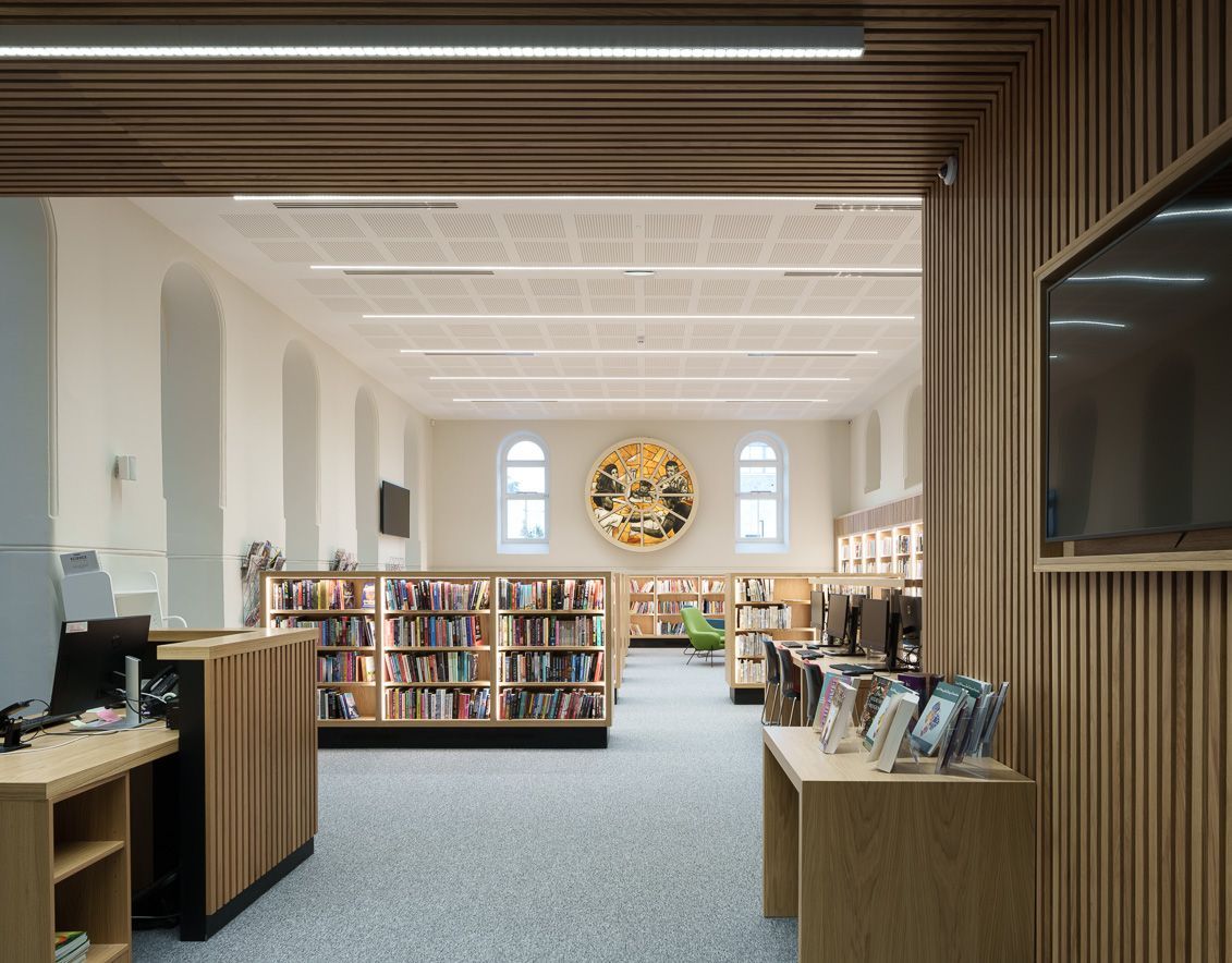 A library with a clock on the wall and a television on the wall.