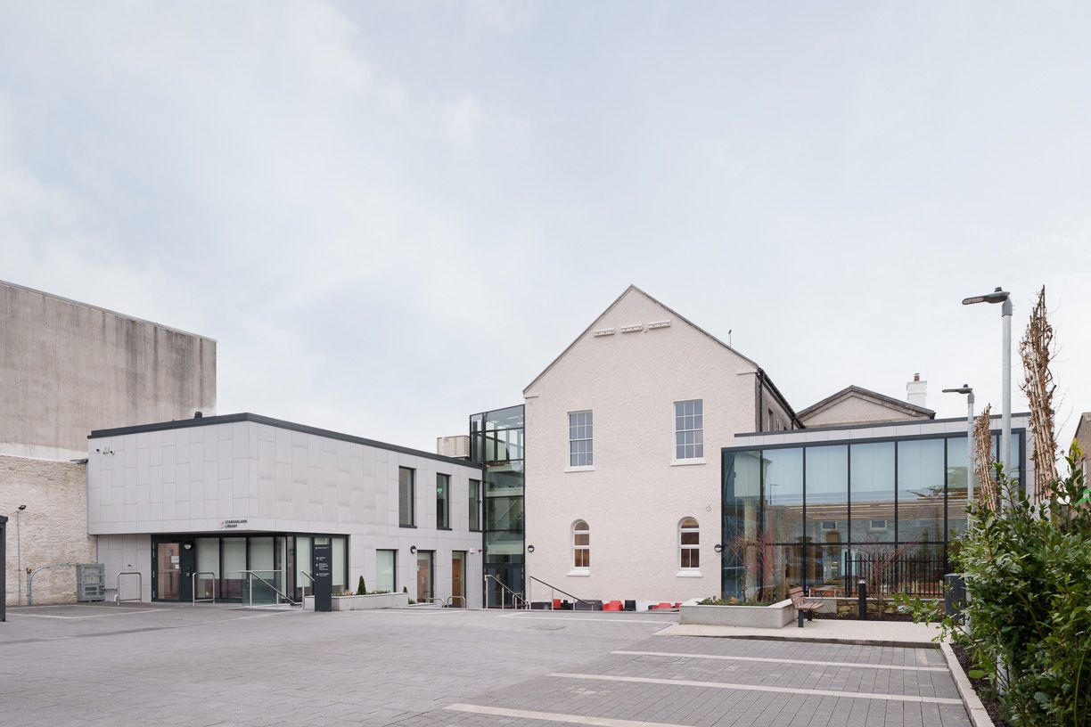 A large white building with a lot of windows and a parking lot in front of it