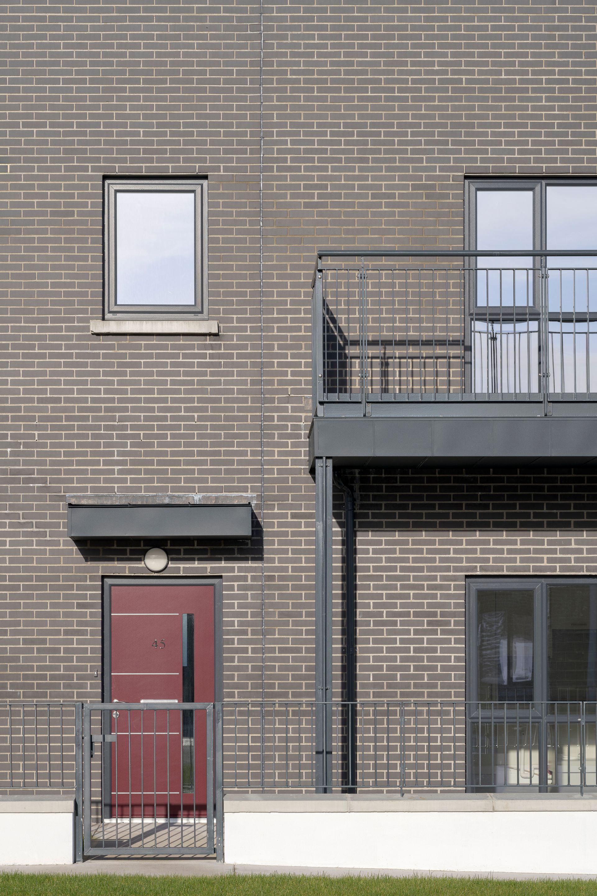 A brick building with a balcony and a red door
