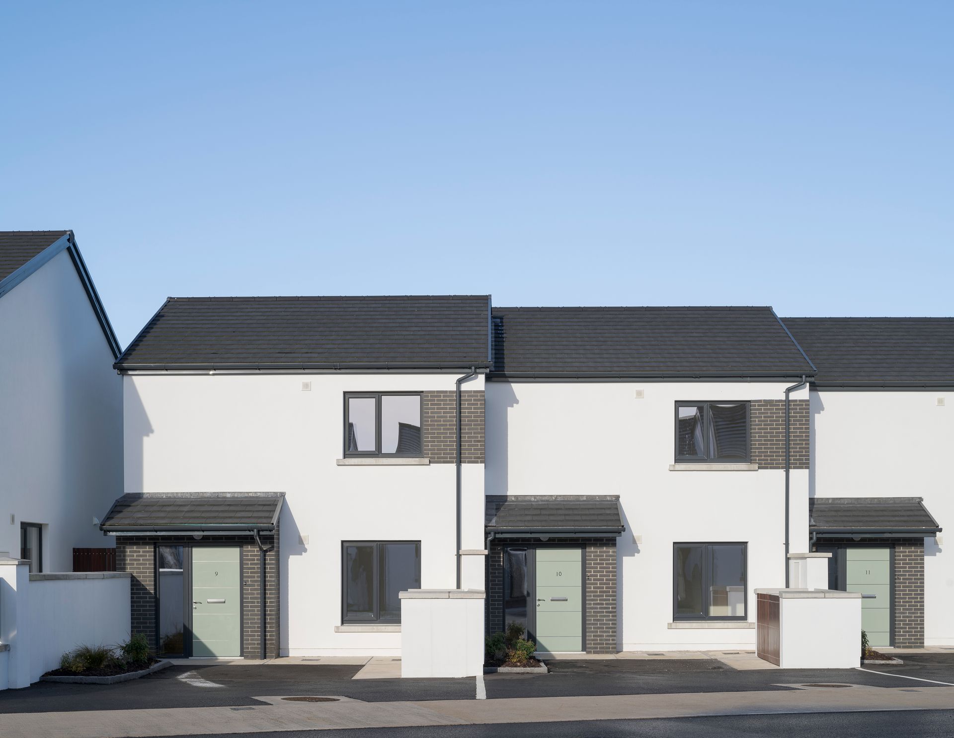 A row of white houses with black roofs and green doors