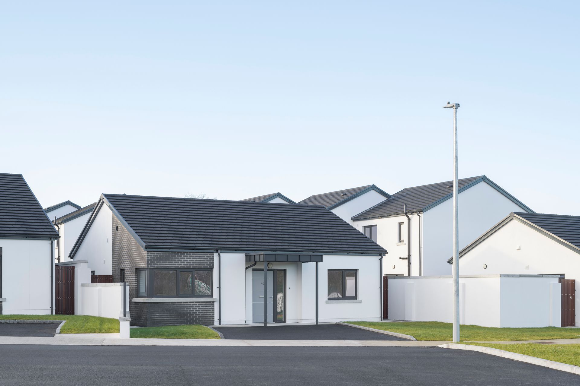A row of white houses with black roofs in a residential area.