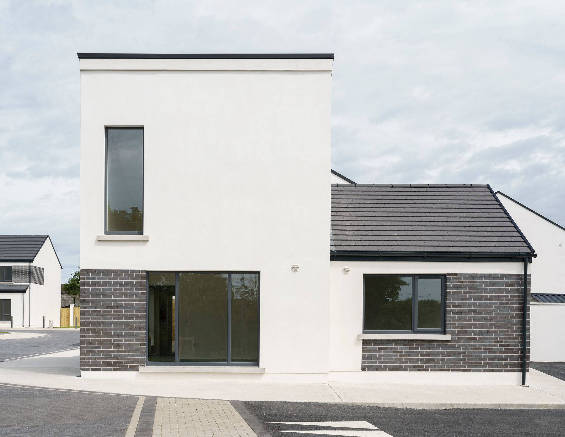 A white house with a black roof and a large window