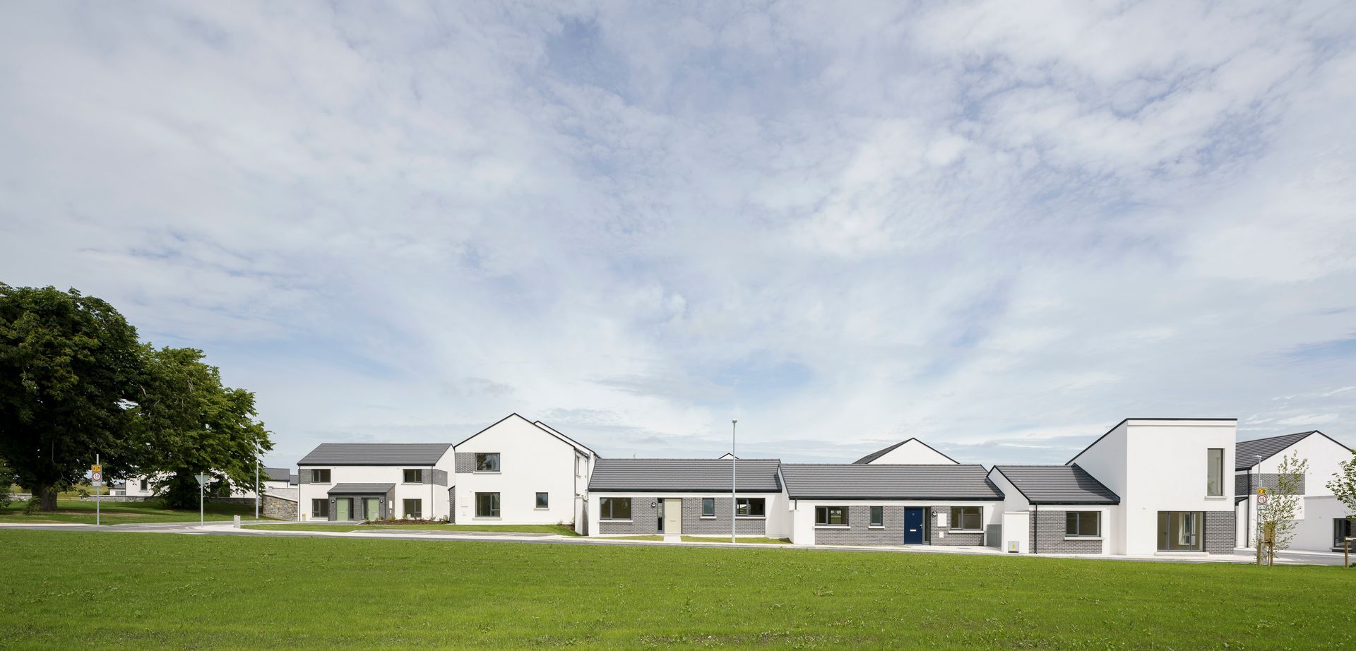 A row of white houses are sitting on top of a lush green field.