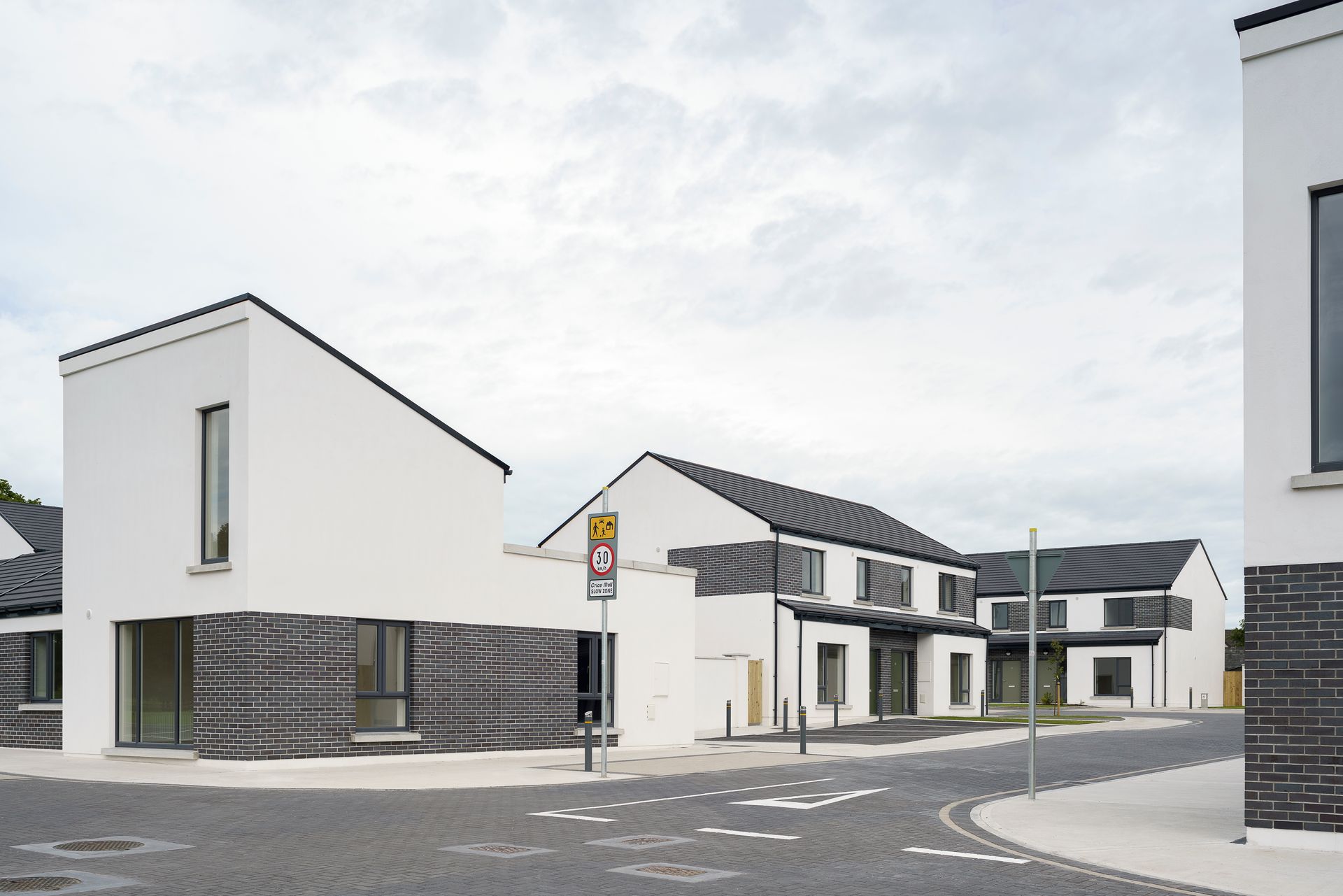 A white building with a black roof is next to a black building