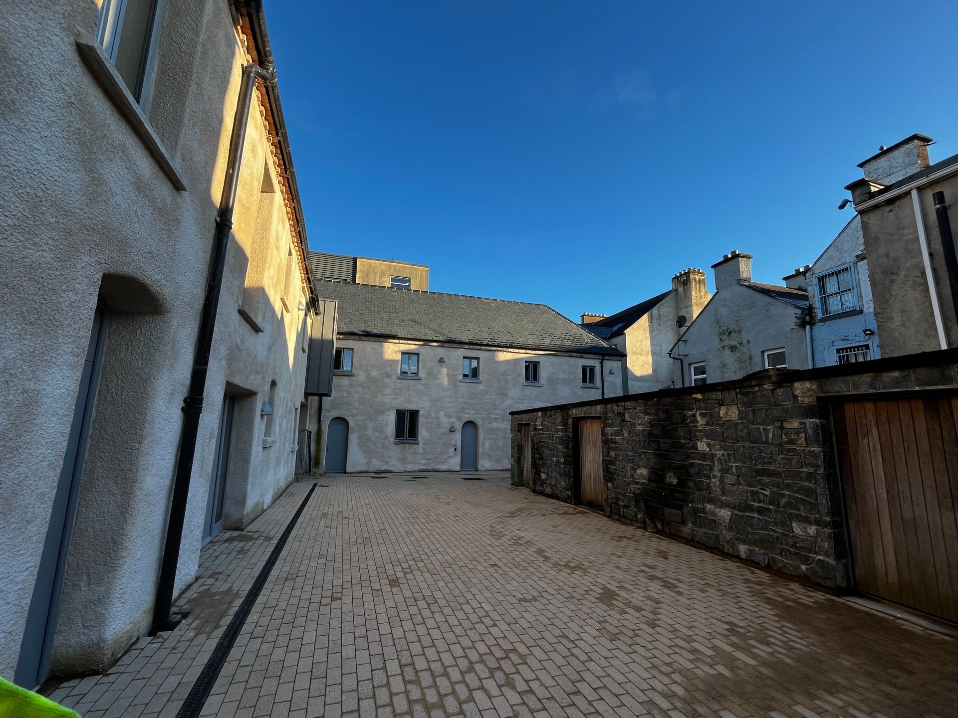 A brick courtyard between two buildings with a blue sky in the background