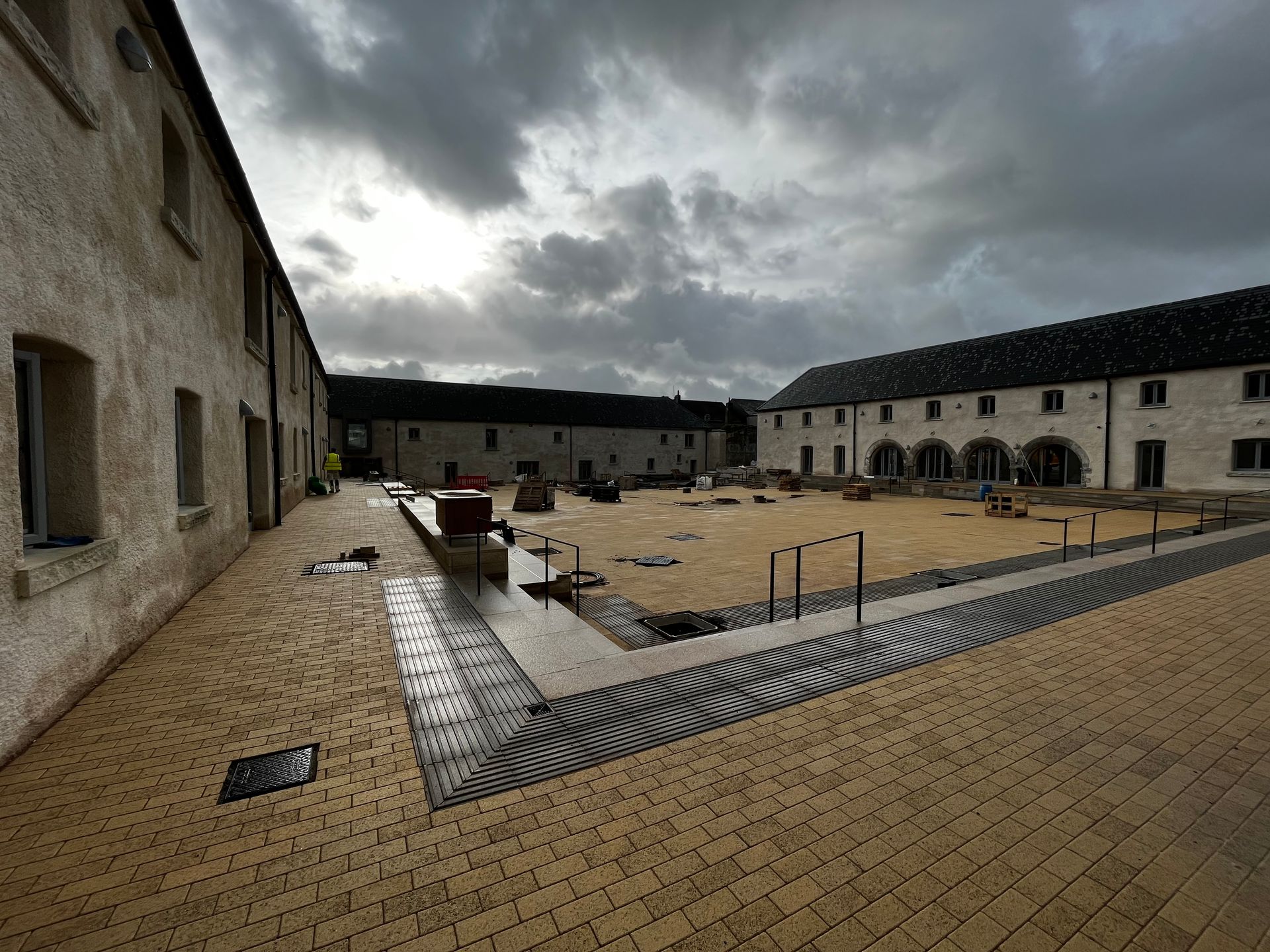 A large brick courtyard surrounded by buildings under a cloudy sky.