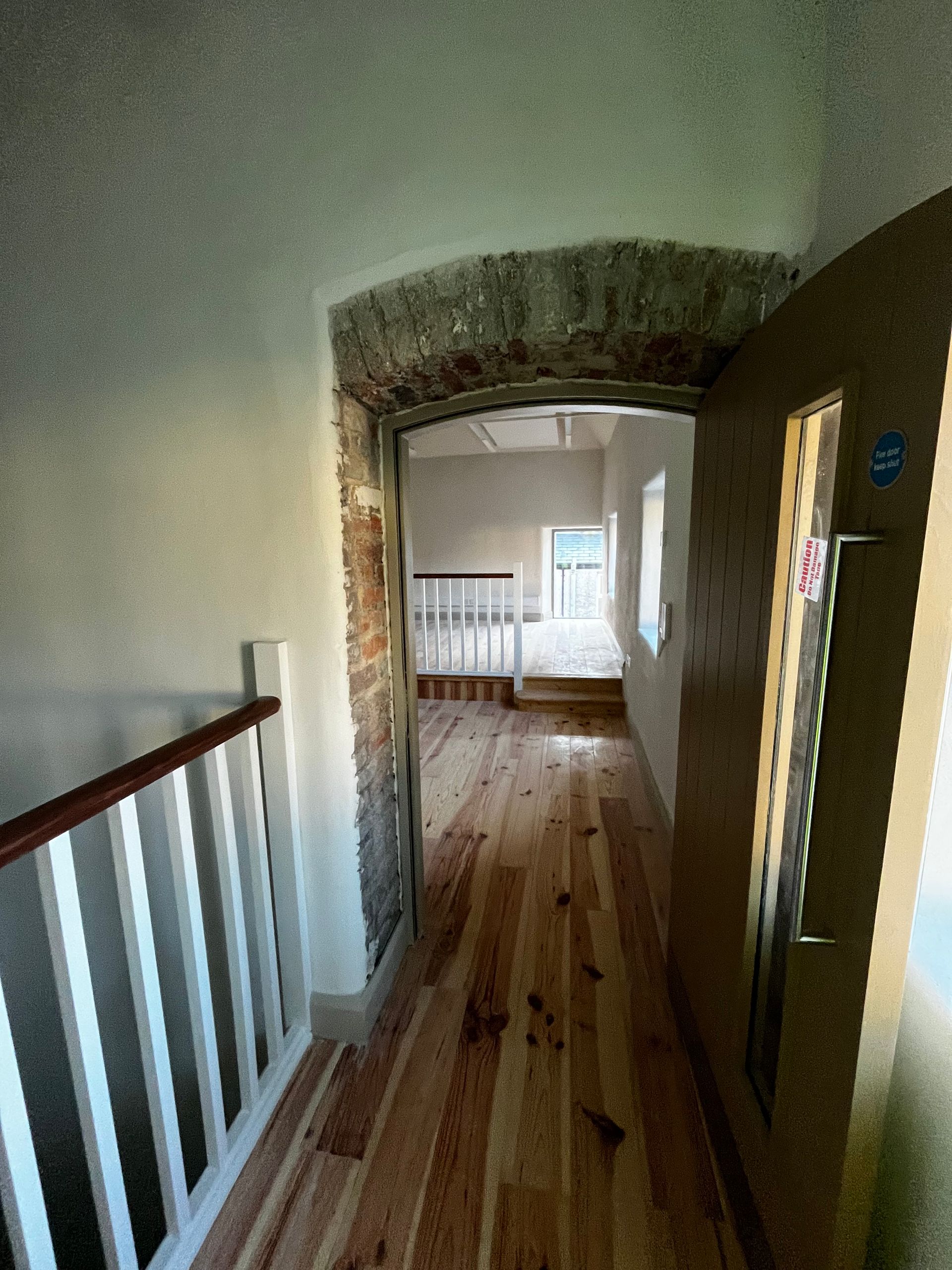 A hallway with wooden floors leading to a bedroom