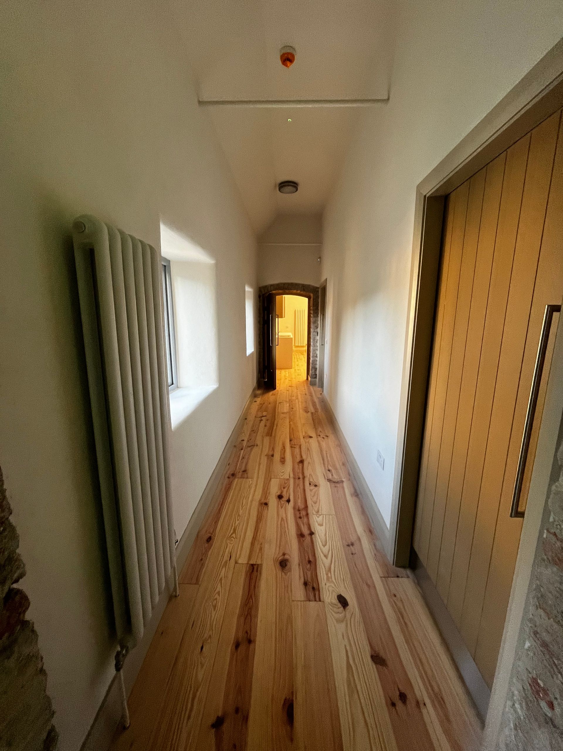 A long hallway with wooden floors and white walls