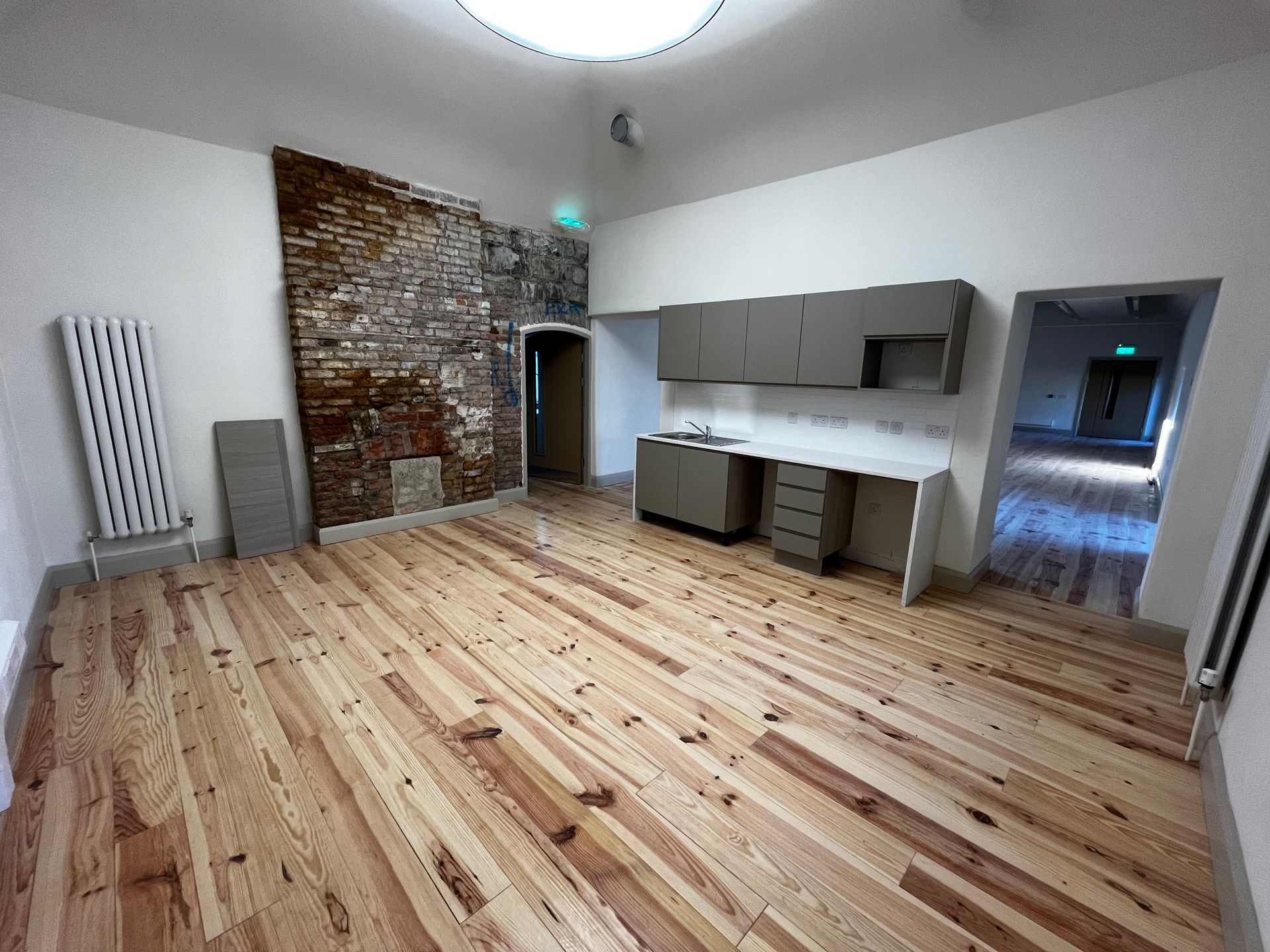 An empty room with wooden floors and a brick wall