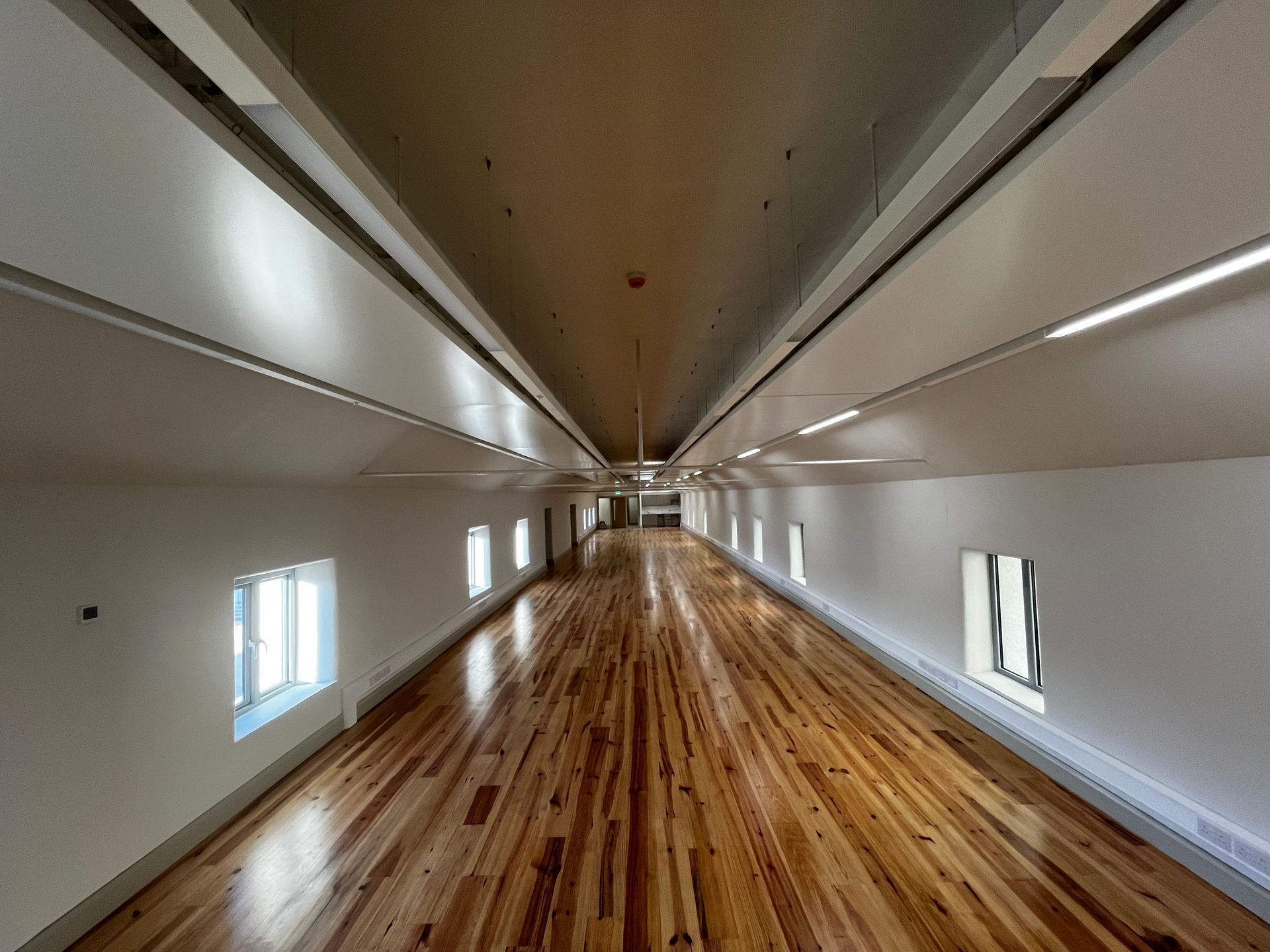 A long hallway with wooden floors and white walls