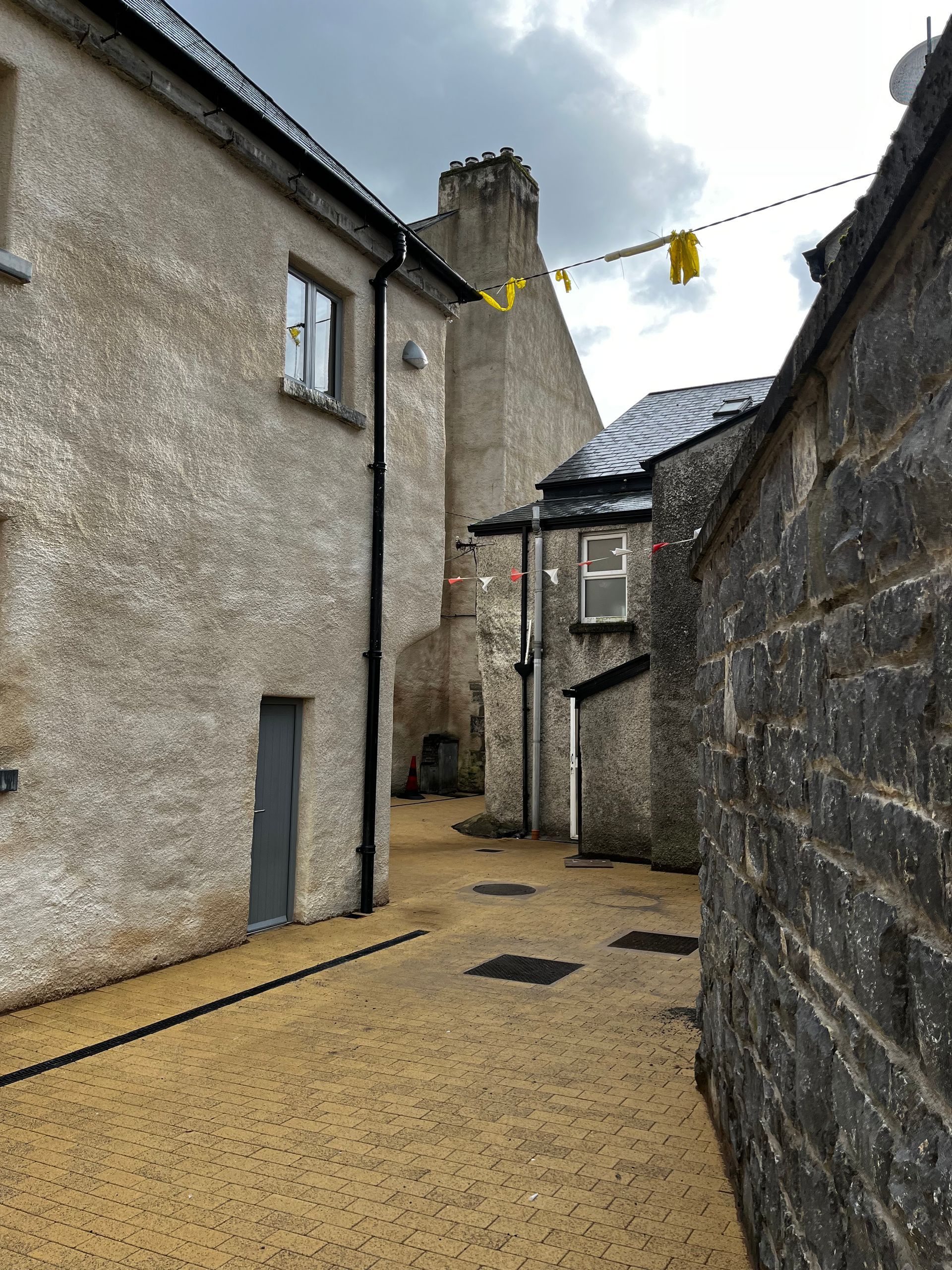 A narrow alleyway between two buildings with a yellow flag hanging from the roof.