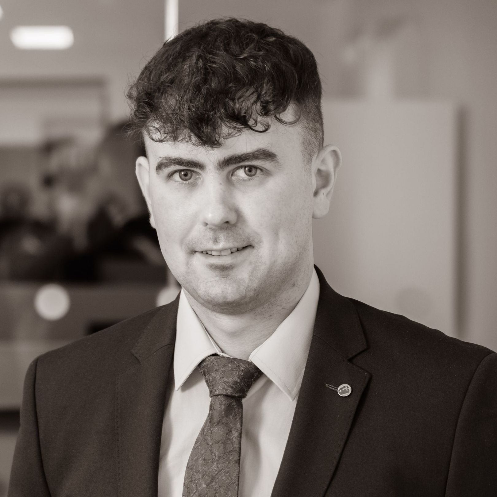 A man in a suit and tie is smiling in a black and white photo.