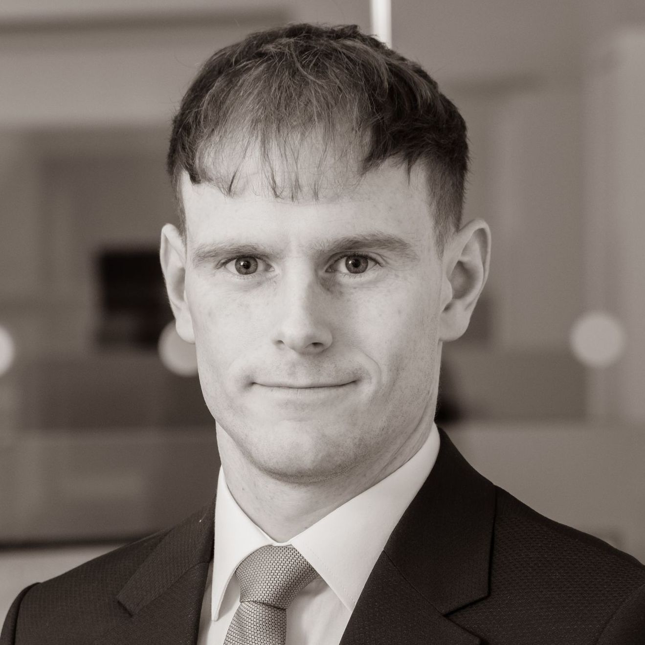 A man in a suit and tie is smiling in a black and white photo.