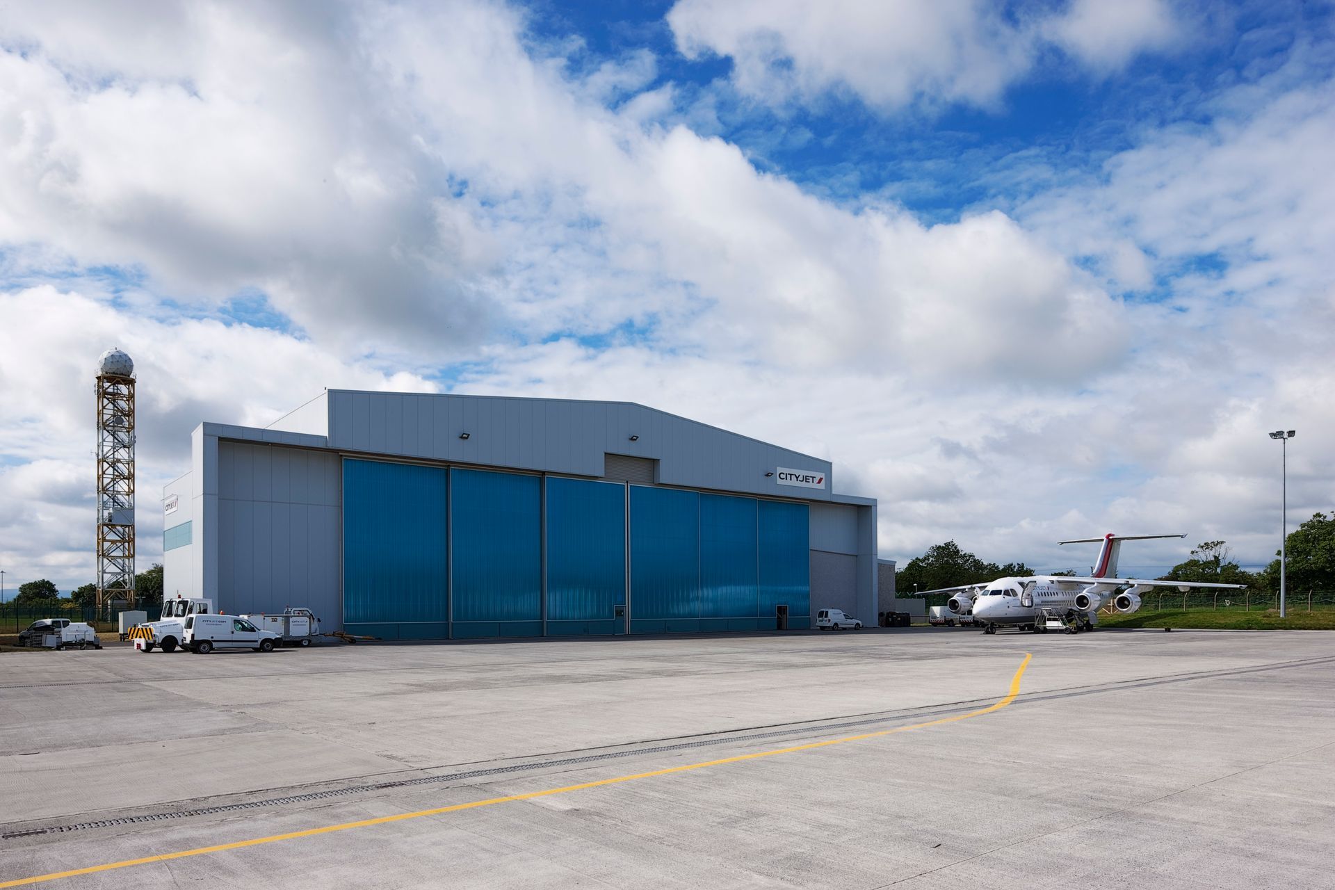 A plane is parked in front of a large hangar.