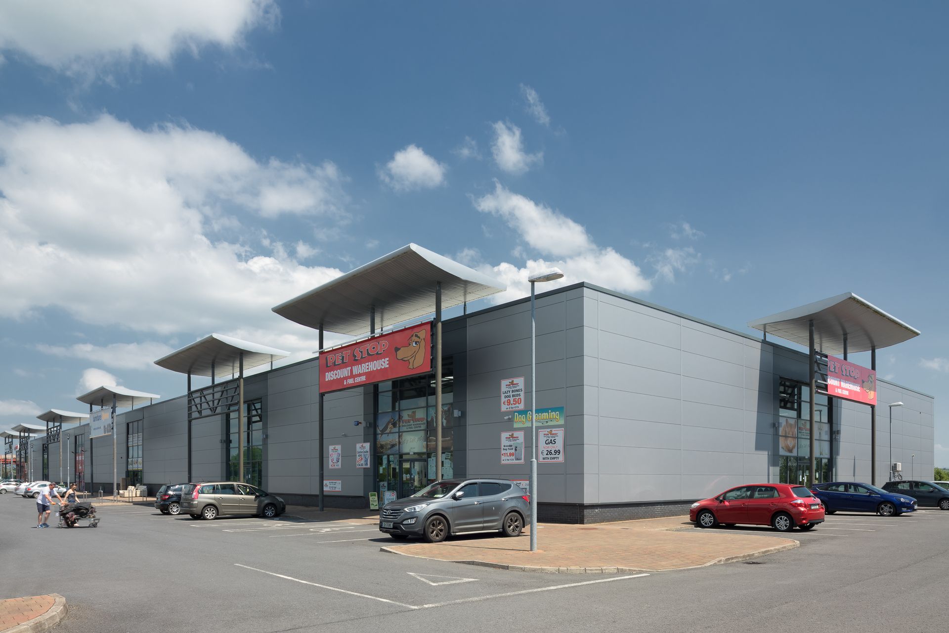 A large building with cars parked in front of it on a sunny day.