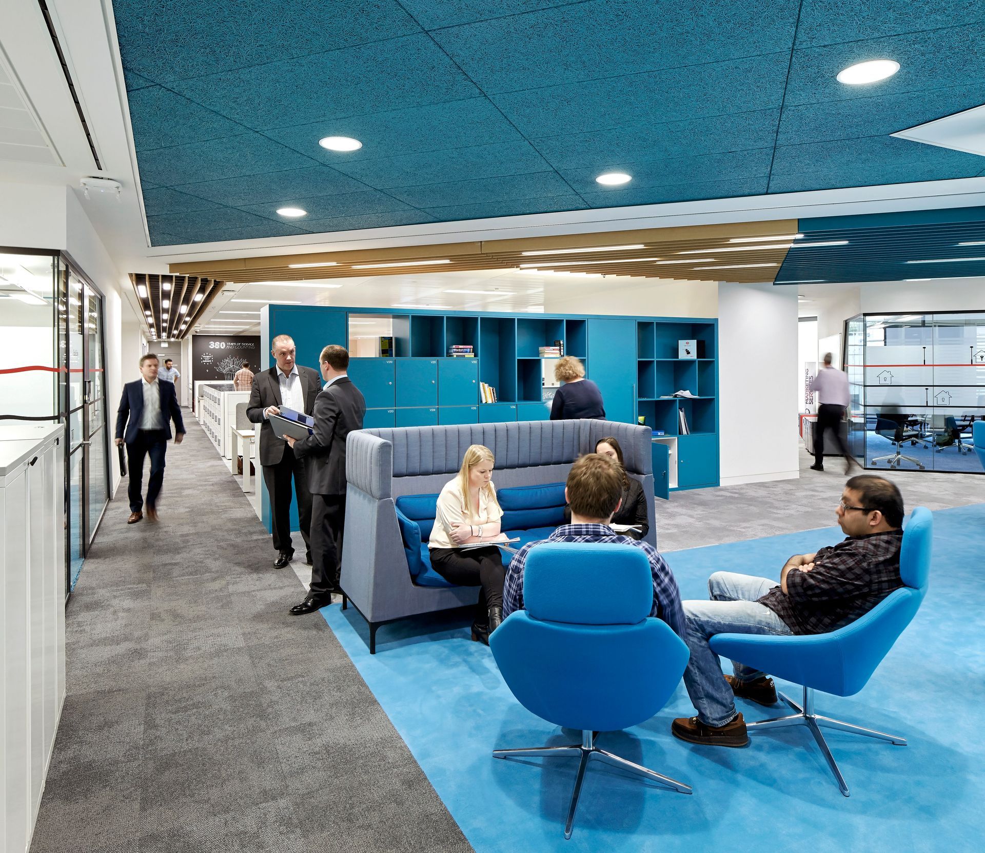 A group of people are sitting in blue chairs in a room