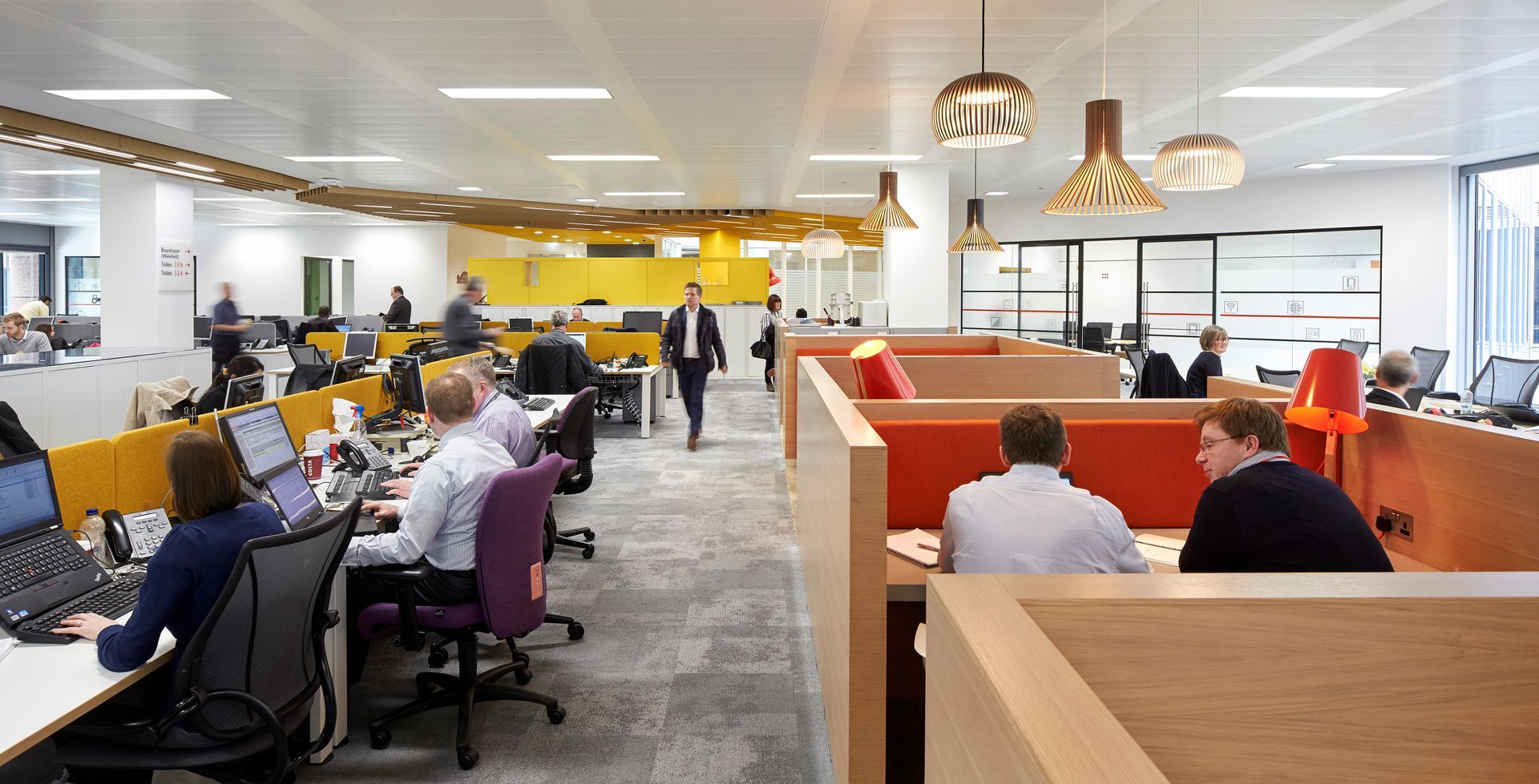 A group of people are sitting at desks in an office.