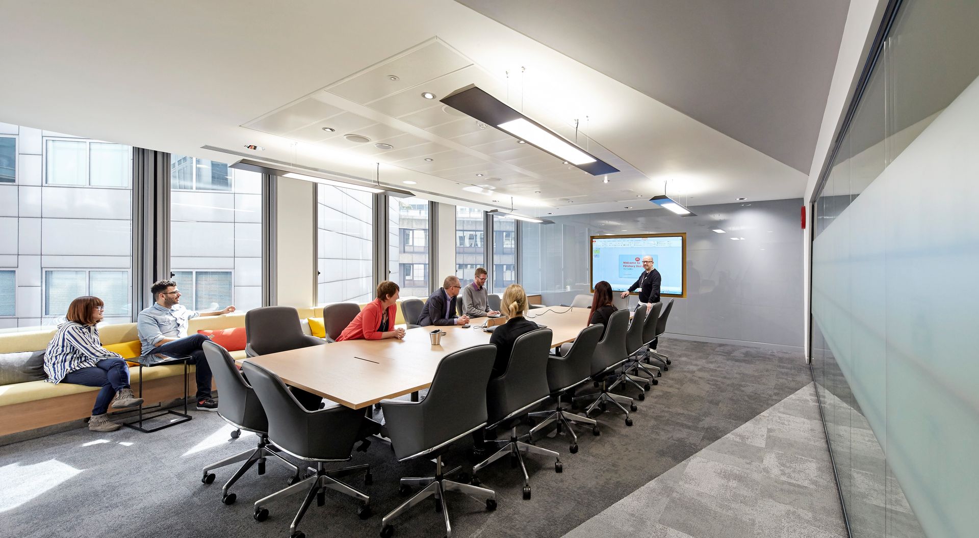 A group of people are sitting around a long table in a conference room.