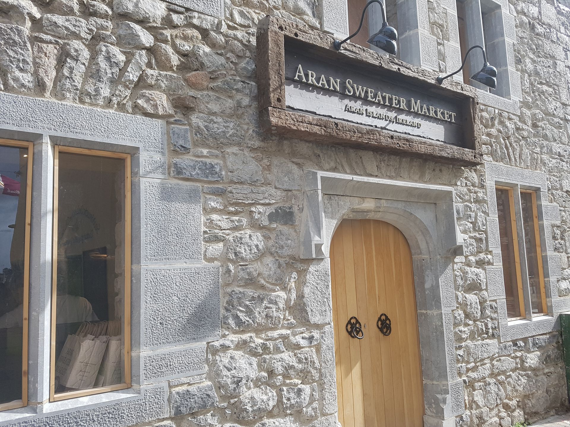 A stone building with a wooden door and a sign that says aran sweater maker