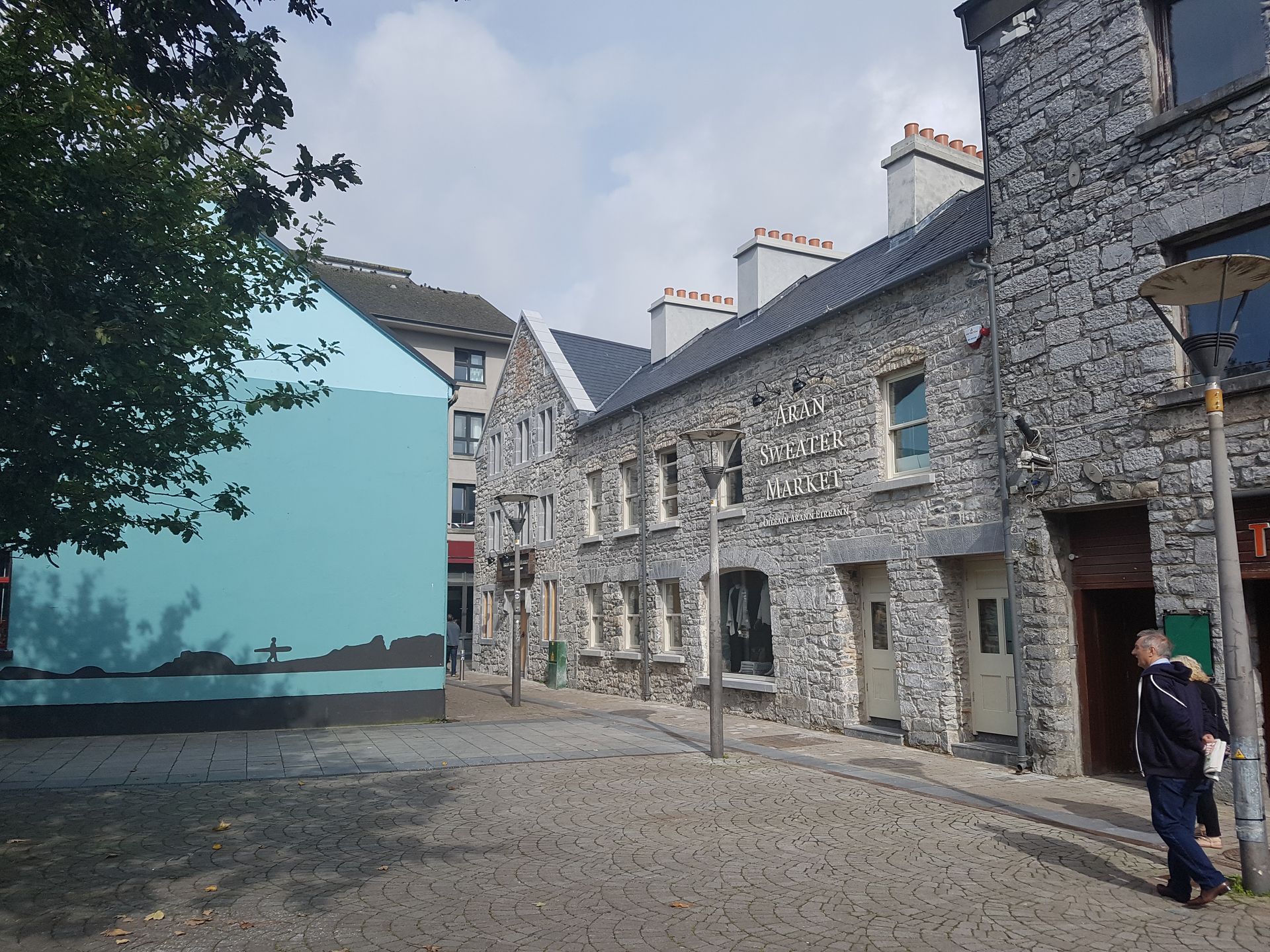 A man walks down a cobblestone street between two stone buildings