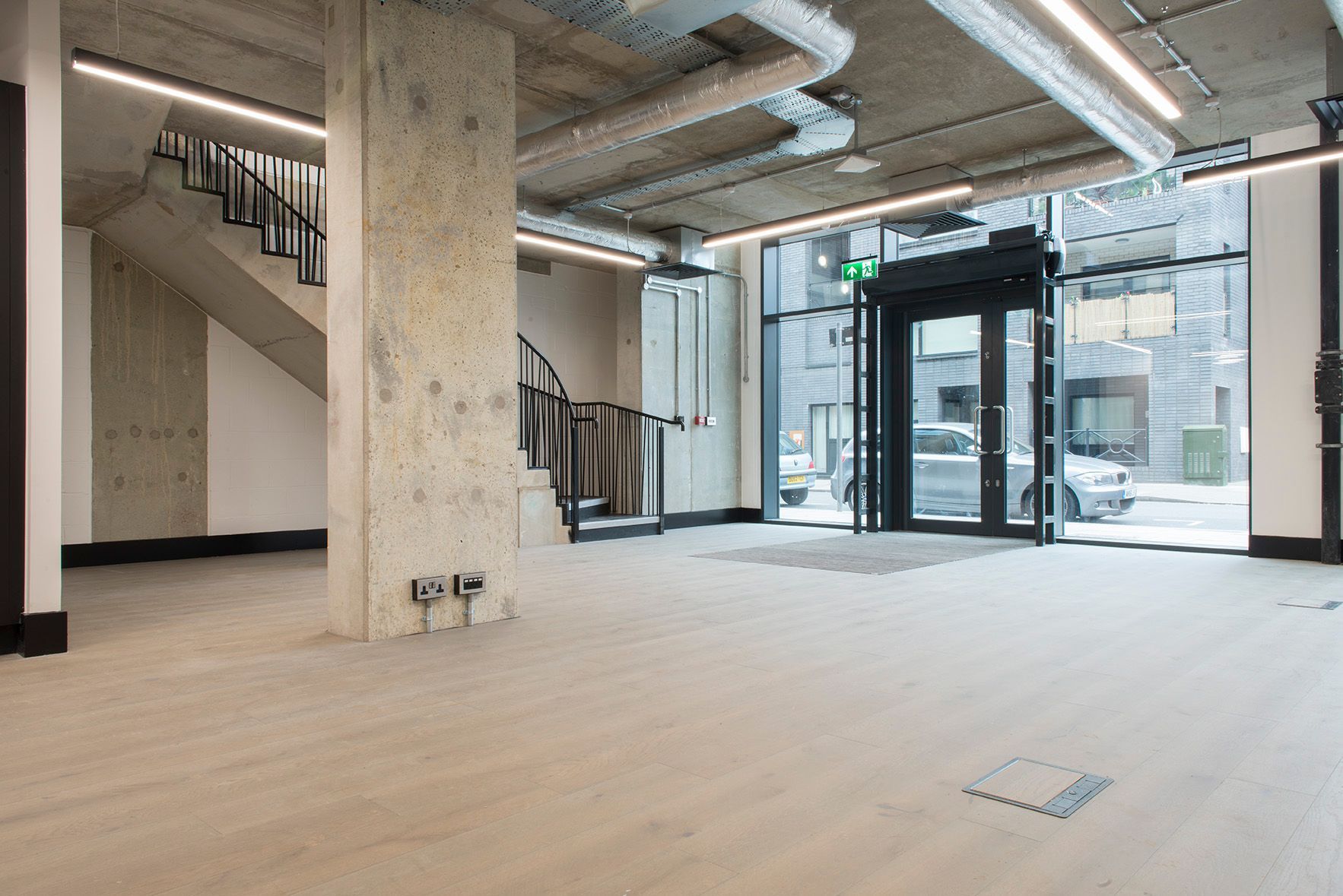 A large empty room with a staircase and a door.