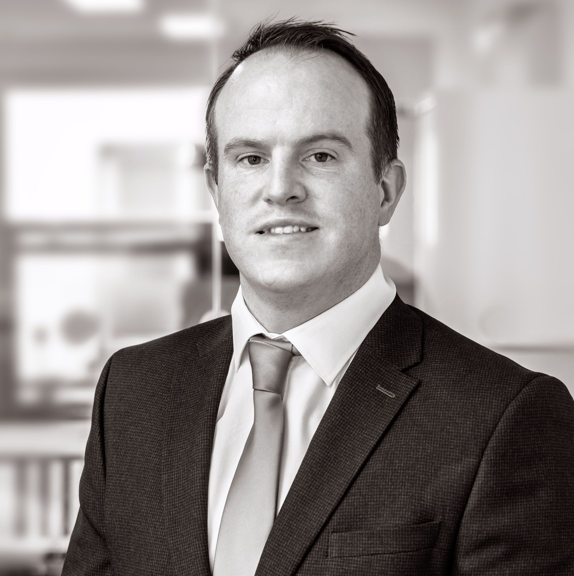 A man in a suit and tie is smiling in a black and white photo.