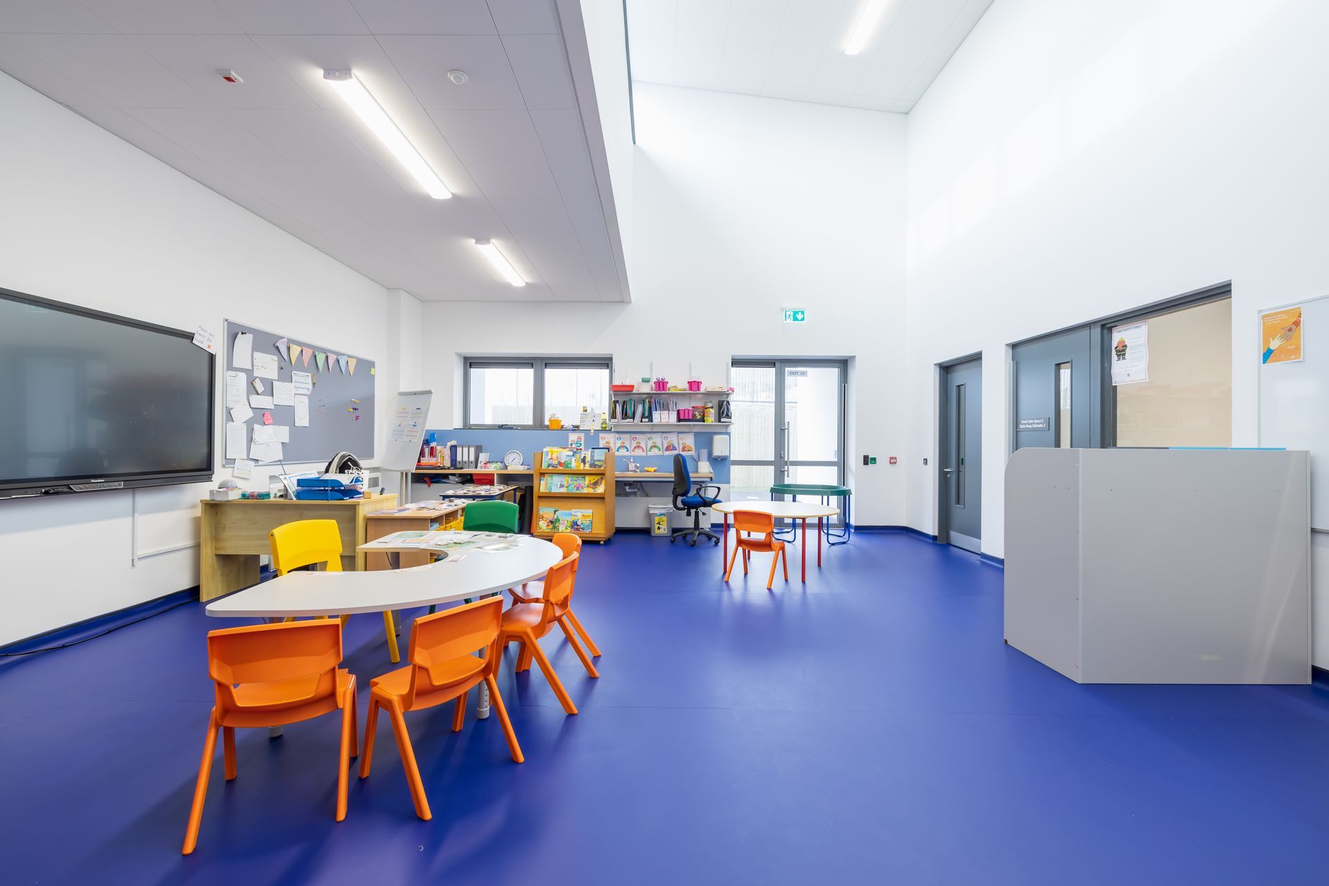 A classroom with blue floors , tables and chairs.