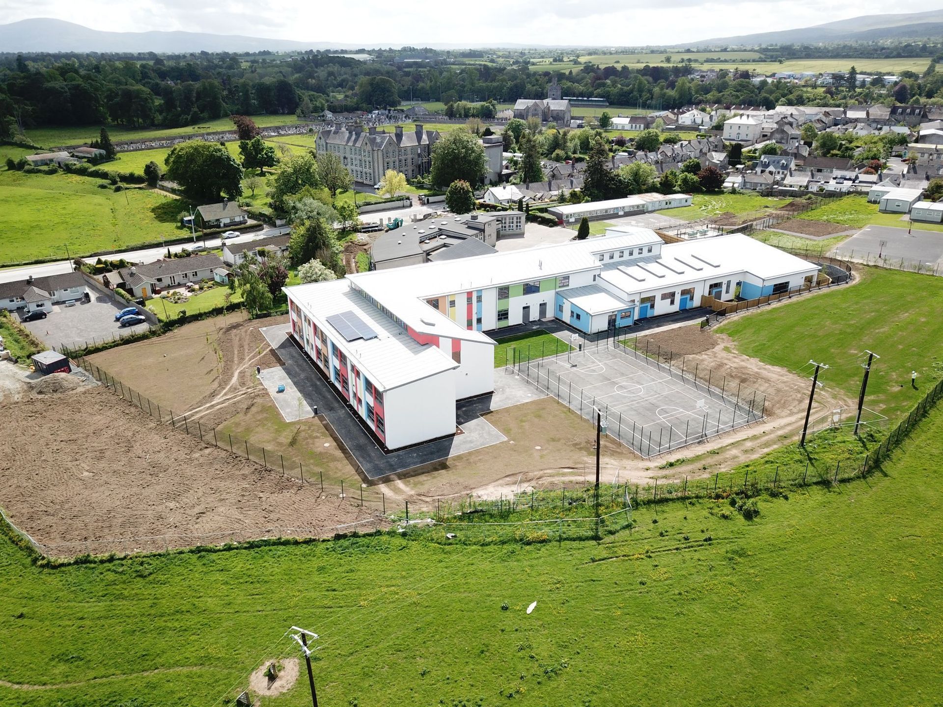 An aerial view of a large white building in the middle of a grassy field.