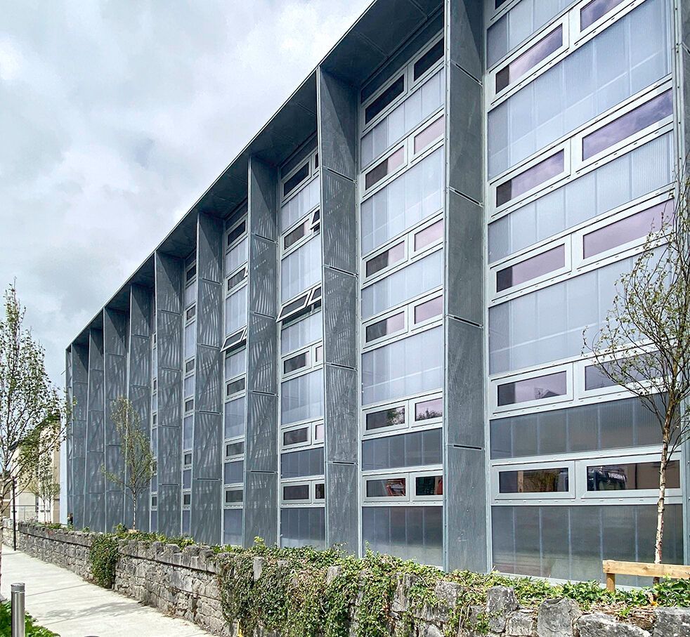 A large building with a lot of windows and a stone wall