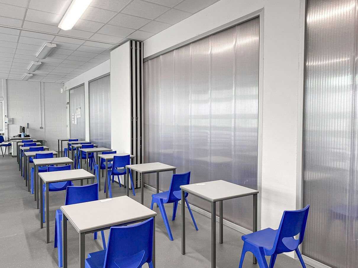 A classroom with blue chairs and white tables.