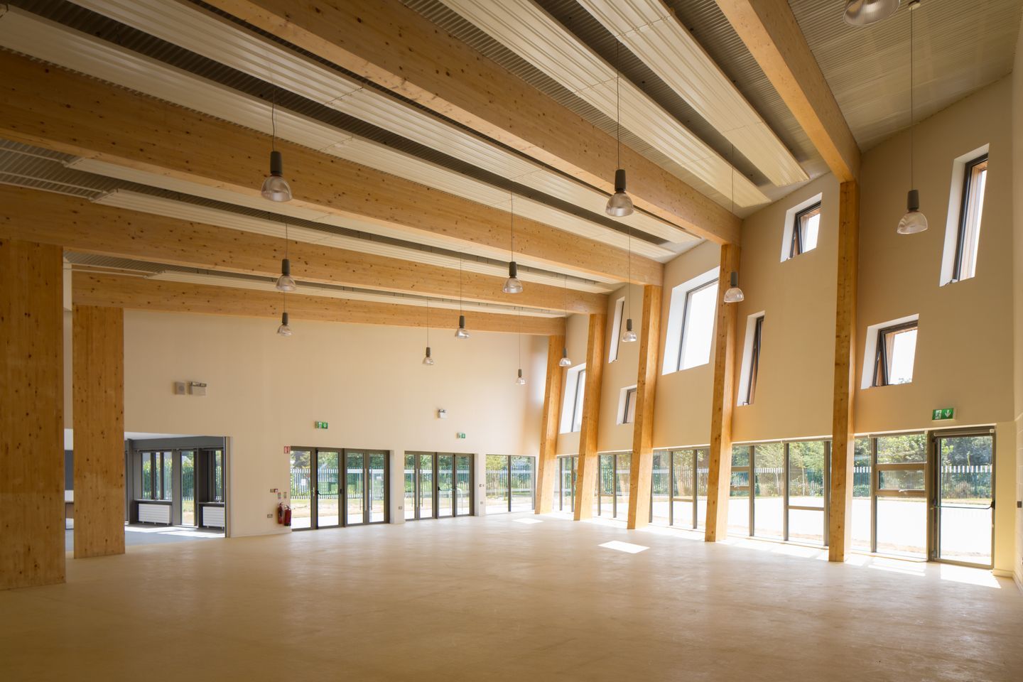 A large empty room with lots of windows and wooden beams