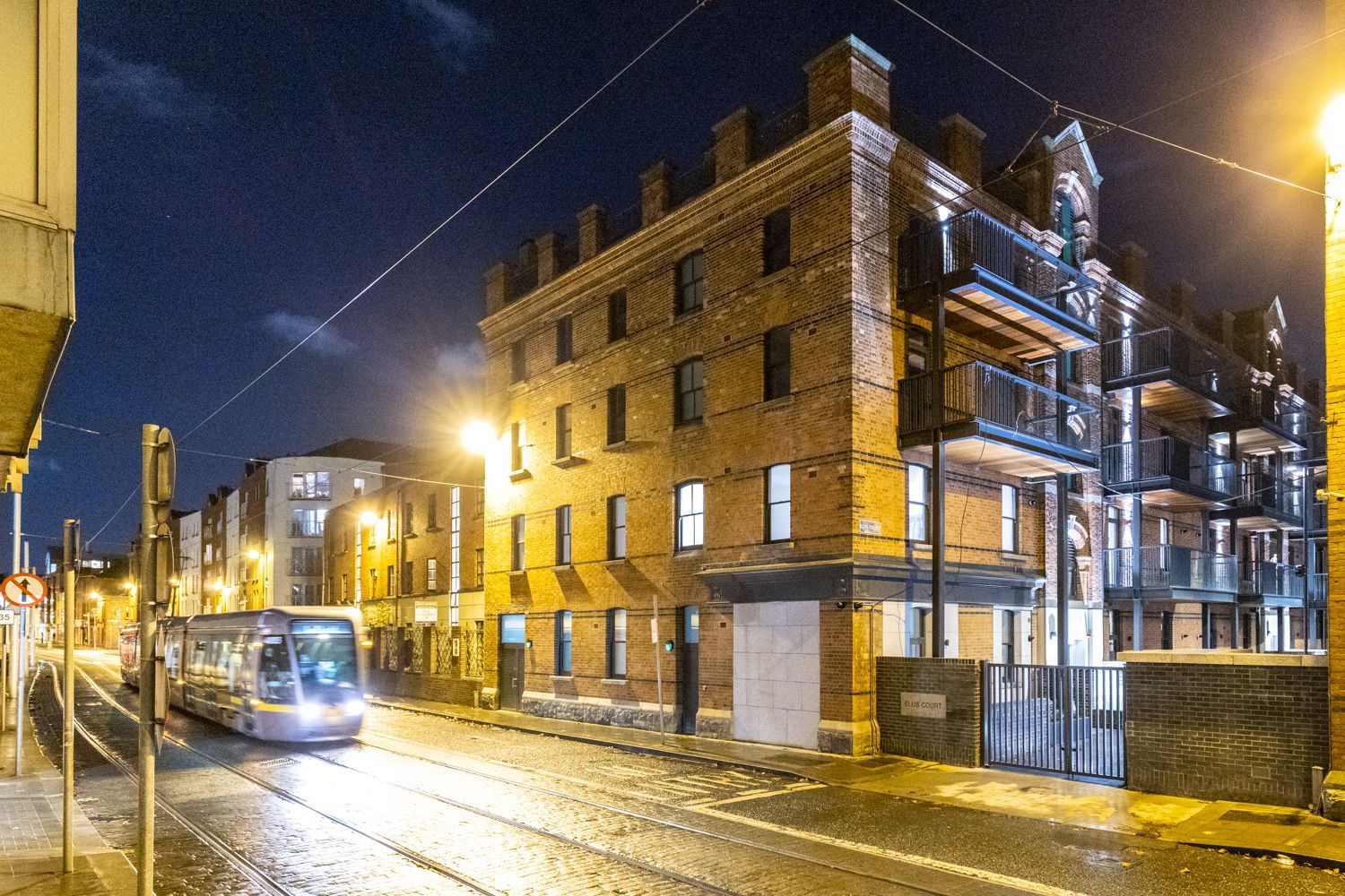 A bus is driving down a street in front of a brick building at night.