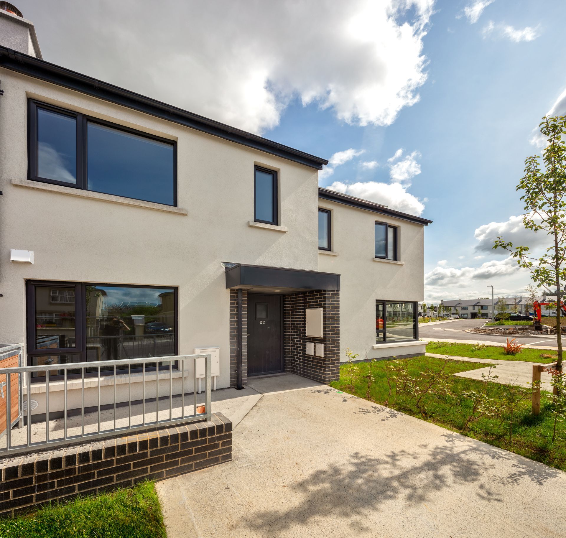 A white house with black windows and a brick fence