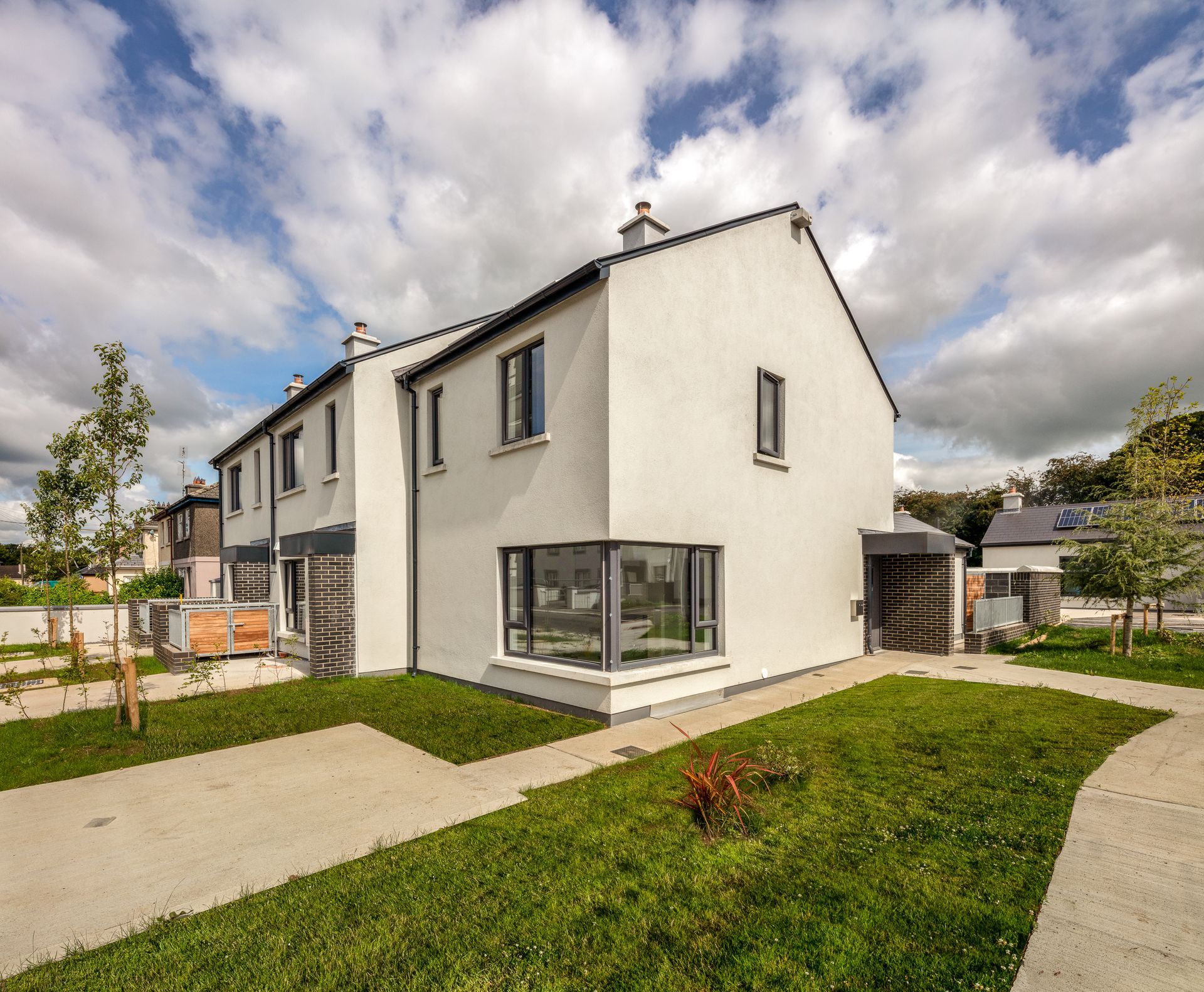 A white house with a lot of windows is surrounded by grass and trees.