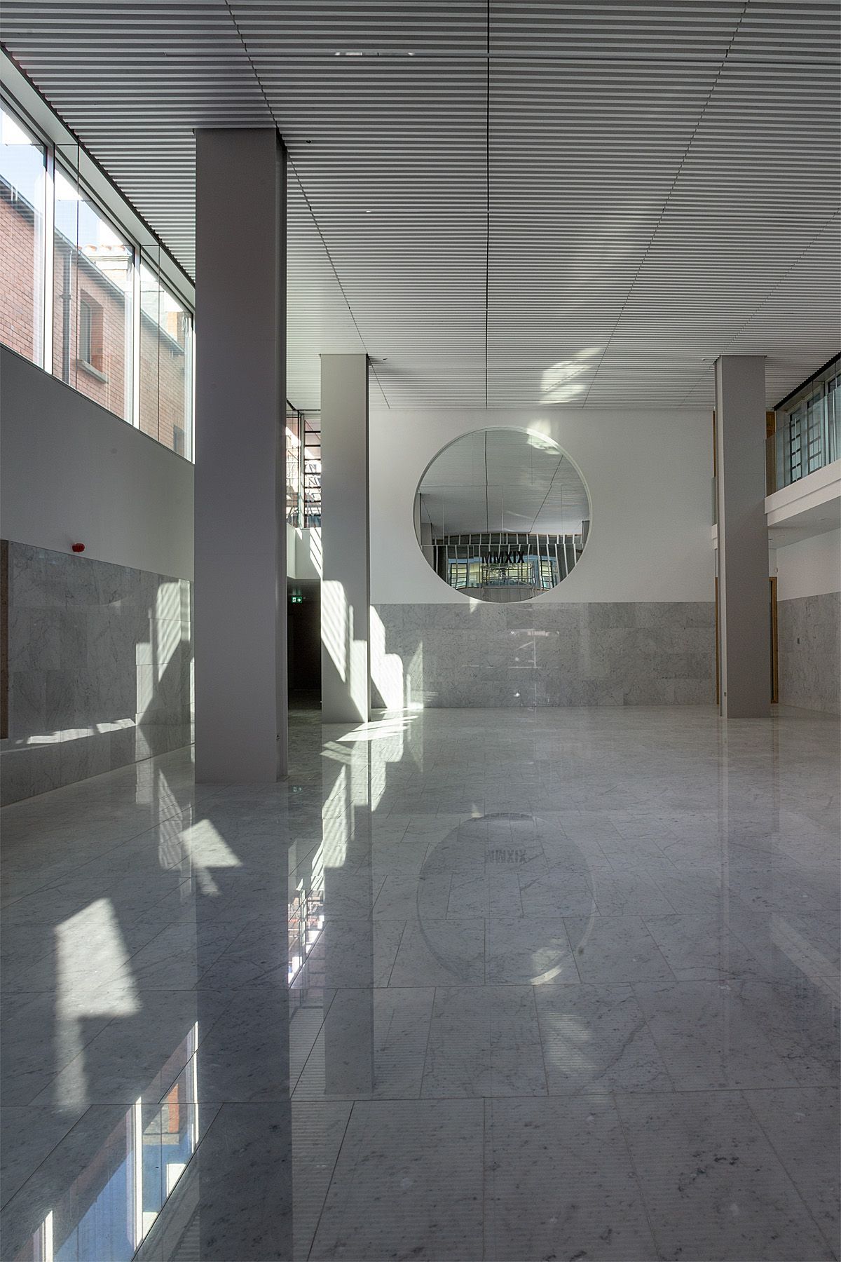 A large empty room with a mirror hanging from the ceiling.