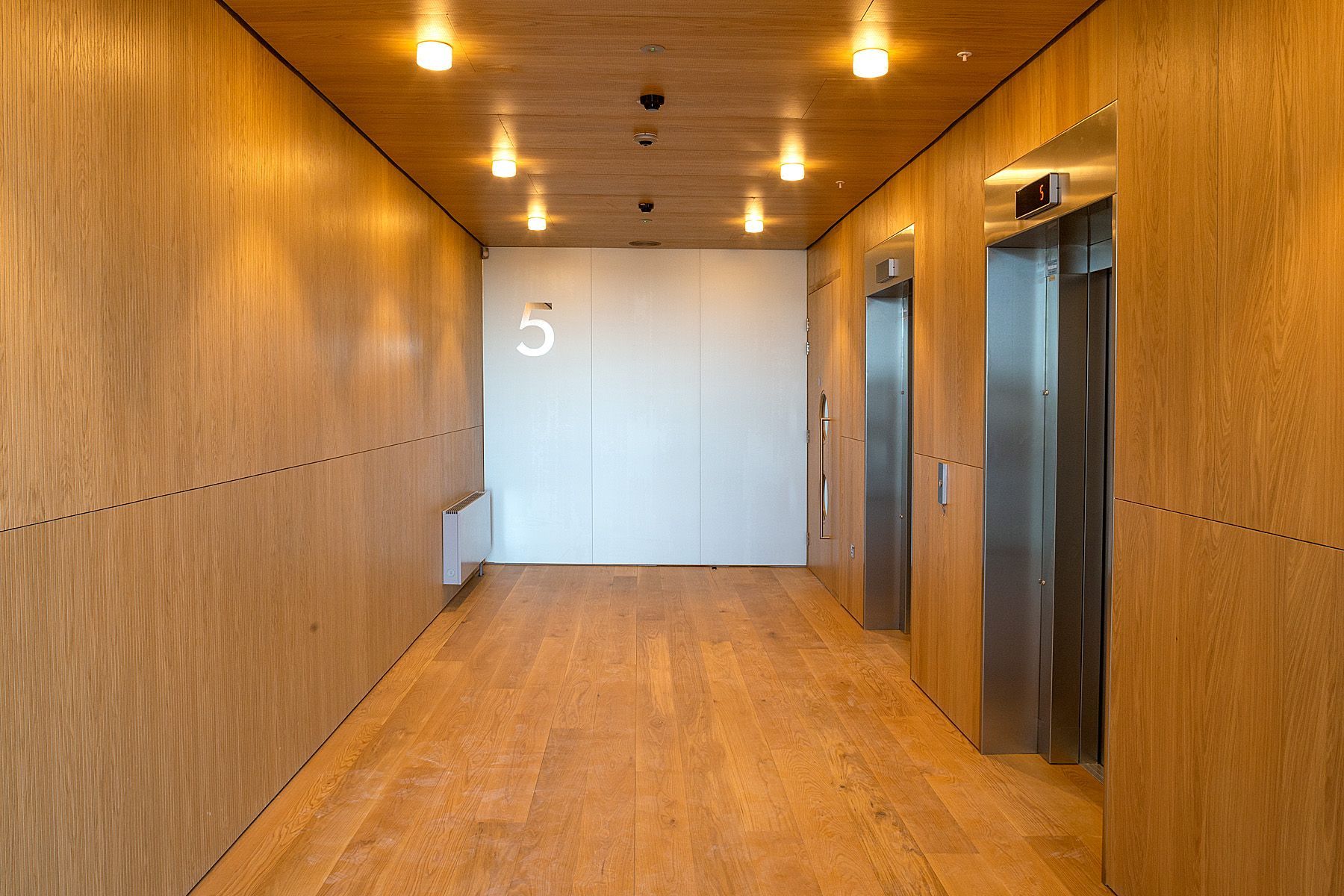A hallway with wooden walls and elevators in a building.